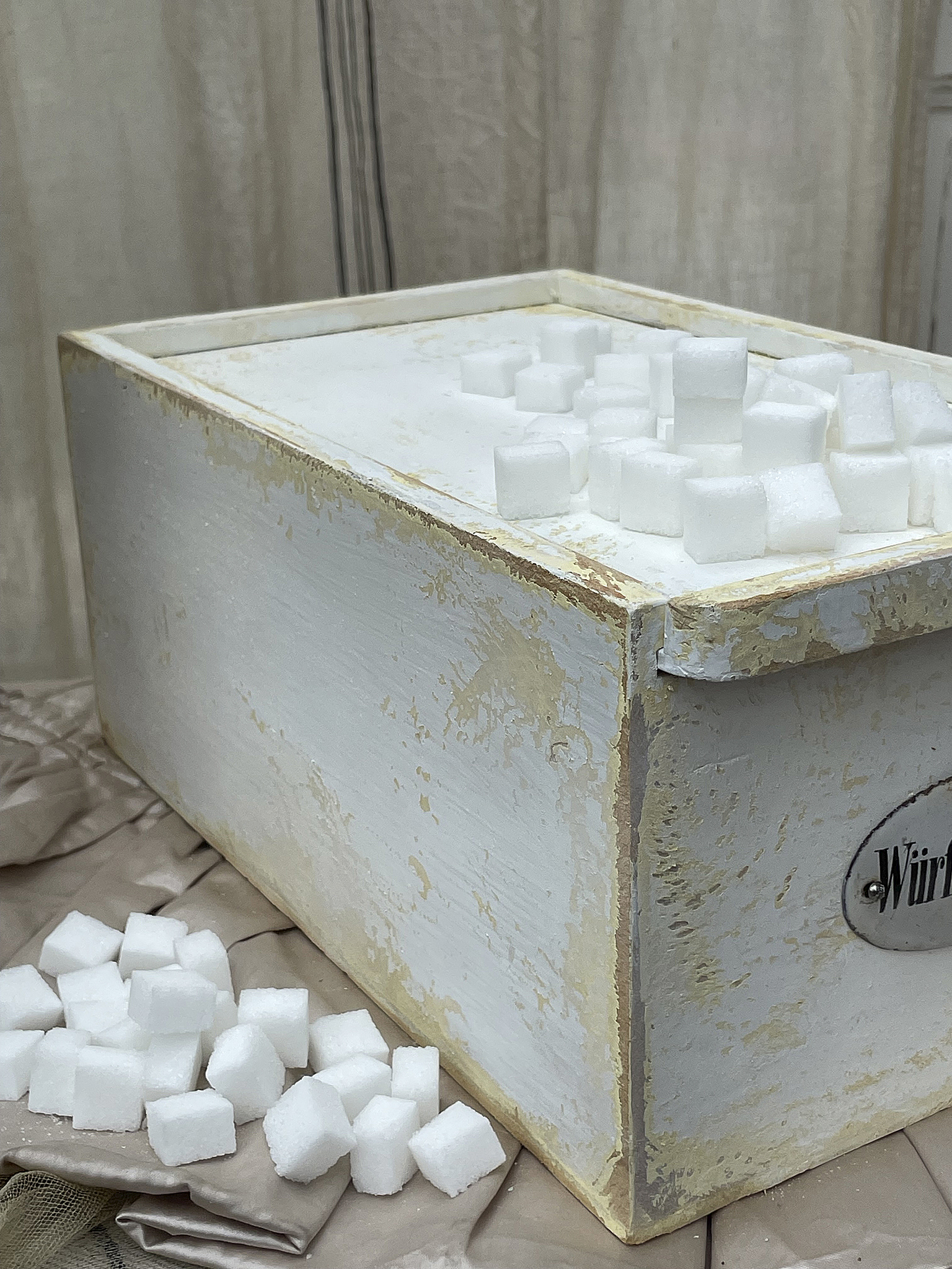 Holzkiste mit Zuckerwürfeln im Vintage-Stil Vintage Holzkiste mit Zuckerwürfeln, die auf einem Tuch liegen