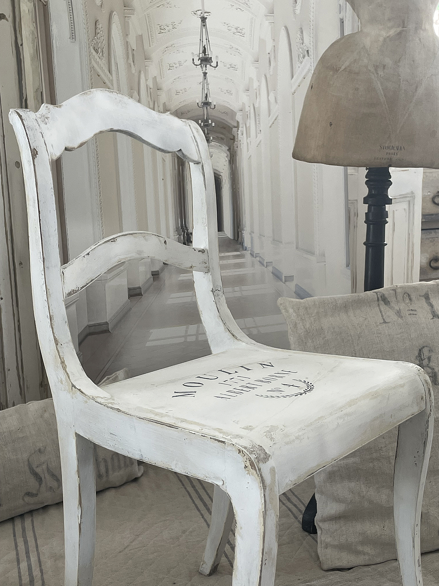 Antiker weißer Stuhl im vintage Stil für gemütliche Wohnräume Weißer antiker Stuhl mit Aufschrift und nostalgischem Design in einem hellen Raum