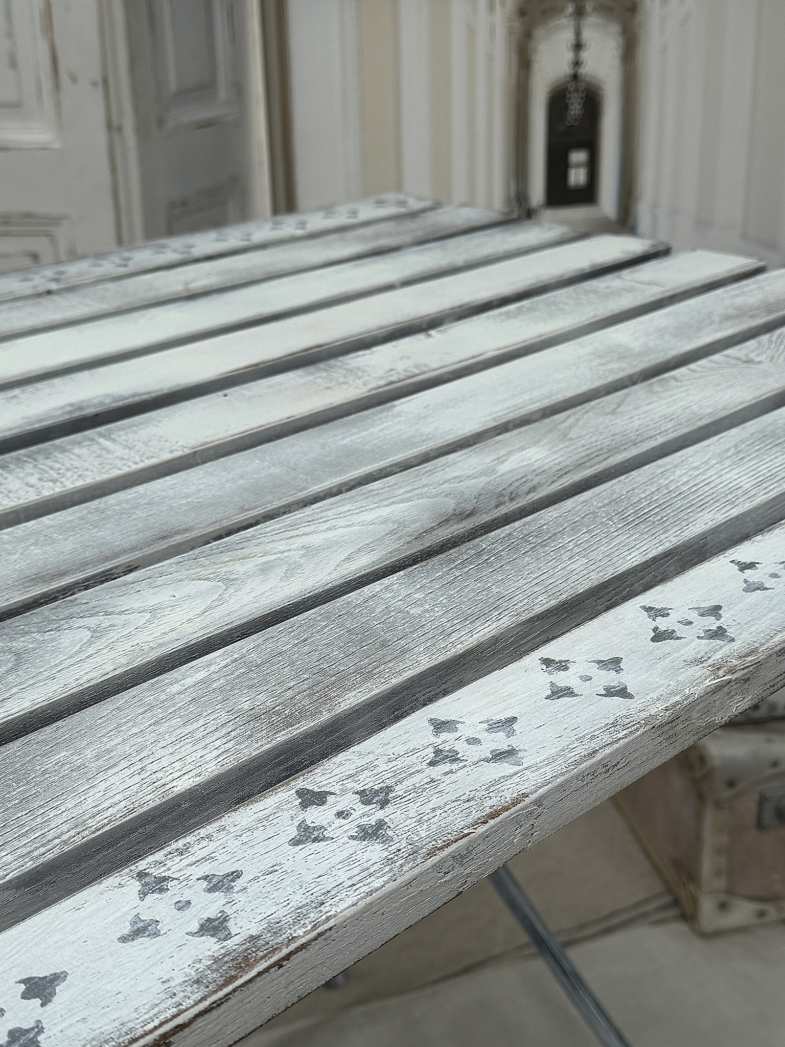 Rustikaler Holztisch mit mattem Finish und zarten Verzierungen Detailansicht eines rustikalen Holztisches mit grauem Finish und floralen Motiven