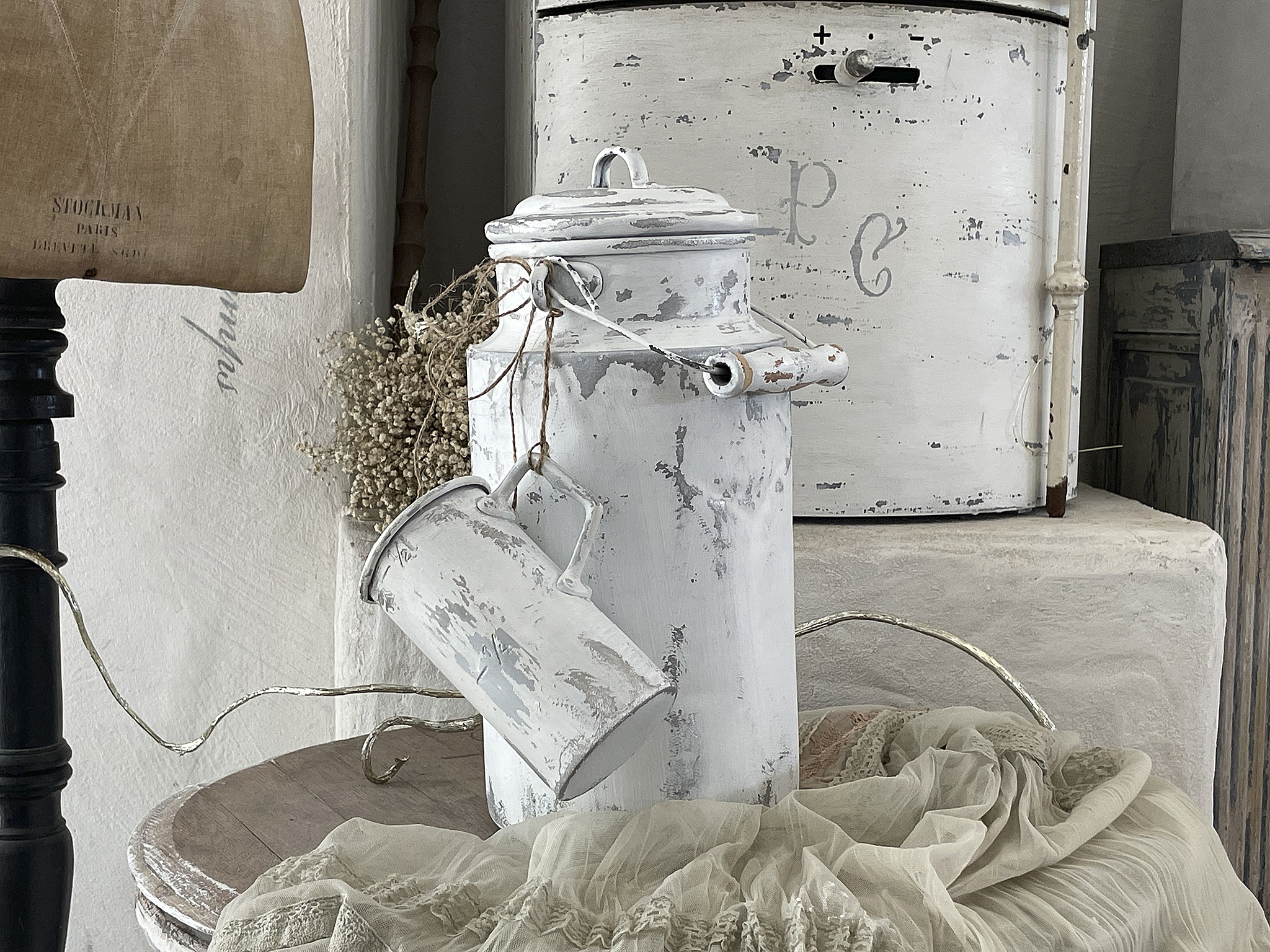 Vintage Milchkannen im Landhausstil für eine rustikale Einrichtung Dekorative Milchkannen in Weiß auf einem Holztisch, umgeben von Vintage-Dekoration
