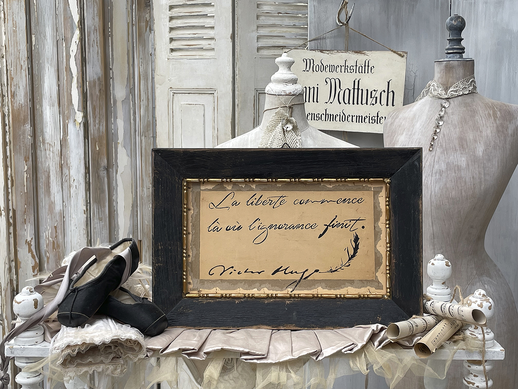Vintage Zitat in schwarzem Rahmen mit eleganter Garderobe Schmuckstück mit Zitat von Victor Hugo, umgeben von Couture-Elementen und Ballettschuhen.
