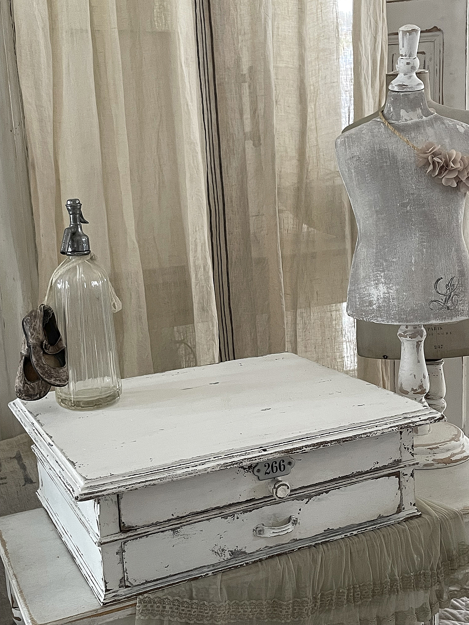 Antike weiße Holzbox mit Schubladen und dekorativen Accessoires Dekorative antike Holzbox mit der Nummer 266, Glasflasche und Schneiderpuppe