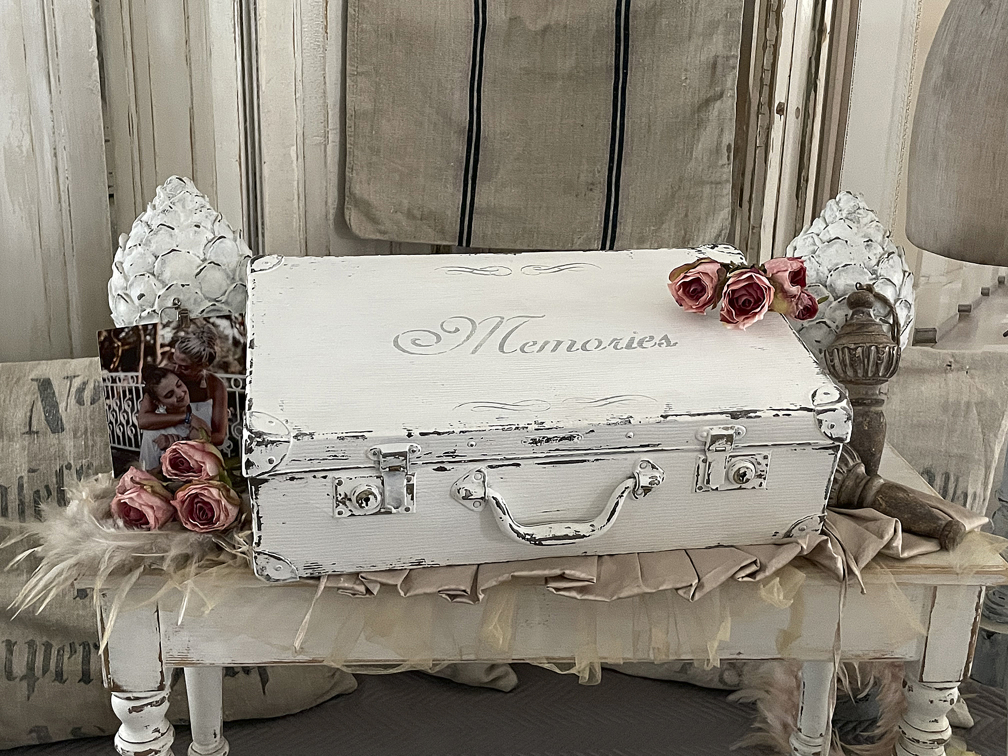 Weißer Koffer mit der Aufschrift 'Memories', dekoriert mit Rosen und persönlichen Erinnerungen