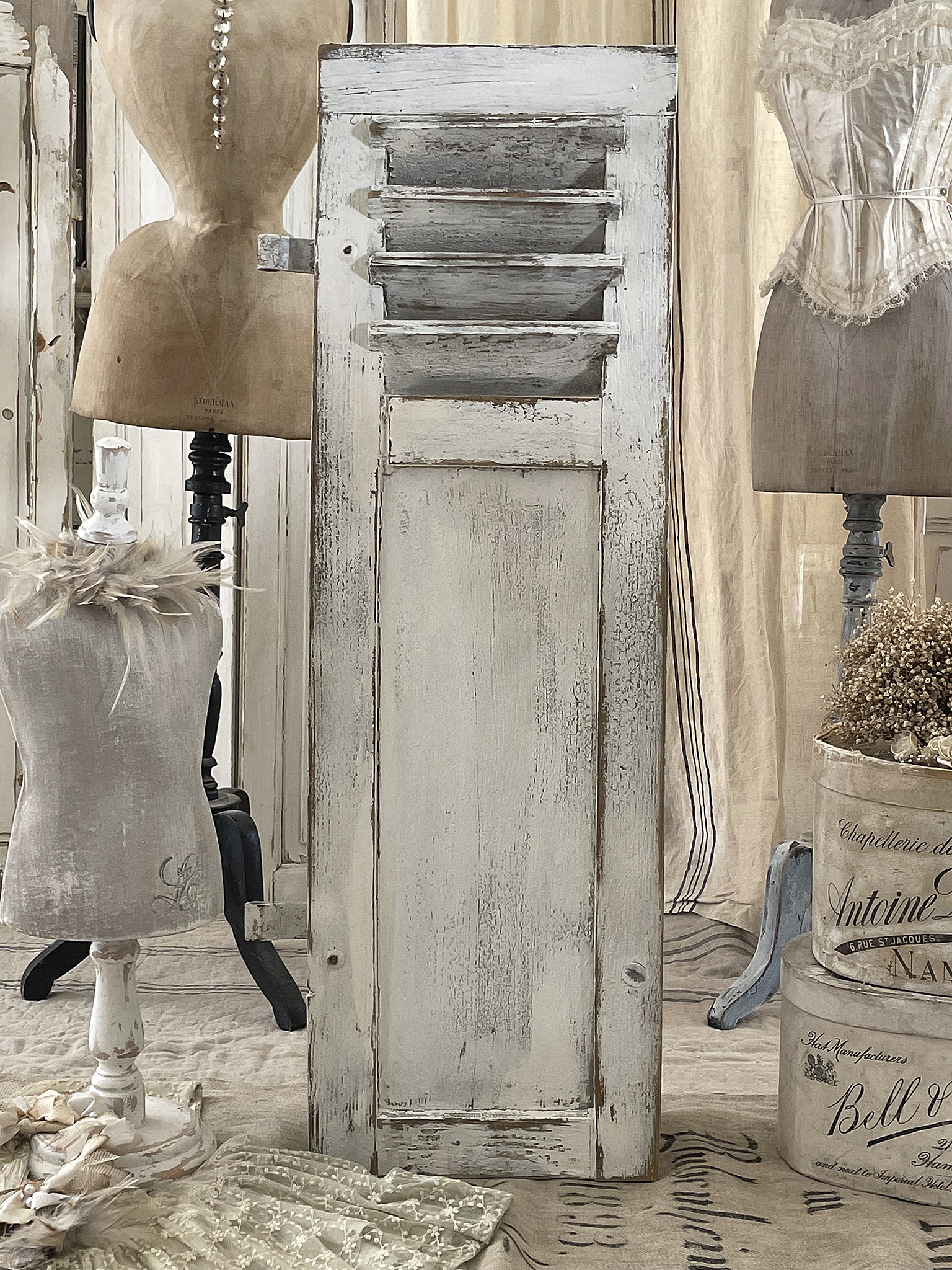 Dekorativer Vintage Holzschrank mit Lufteinlass und Mannequin Rustikaler Holzschrank mit Lufteinlass in einer stilvollen Umgebung, umgeben von Mannequins und Dekoration.