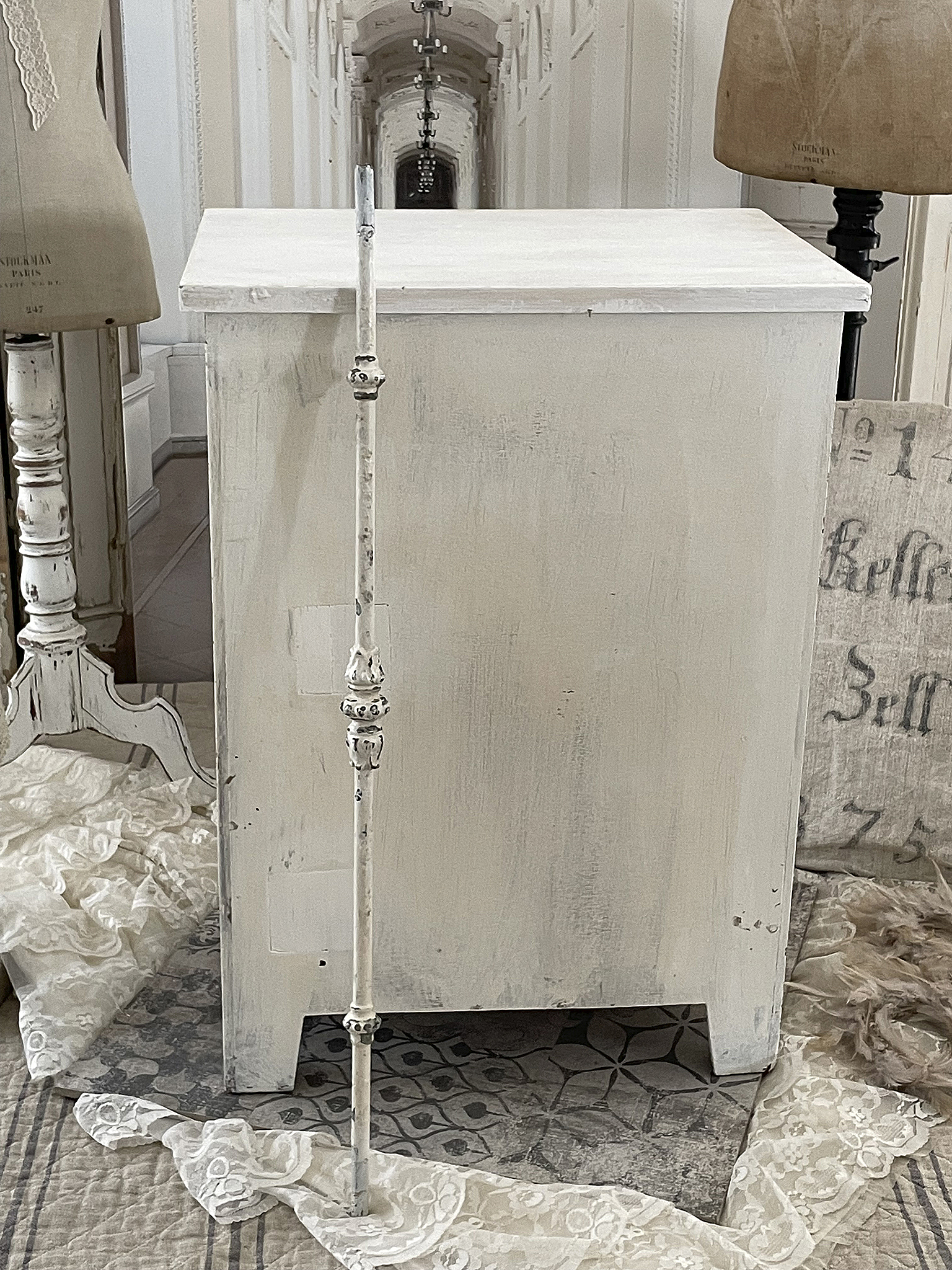 Rustikaler weißer Kasten mit dekorativen Details Rustikaler Kasten in Weiß mit eleganten Verzierungen und einer dekorativen Stange, ideal für den Landhausstil.