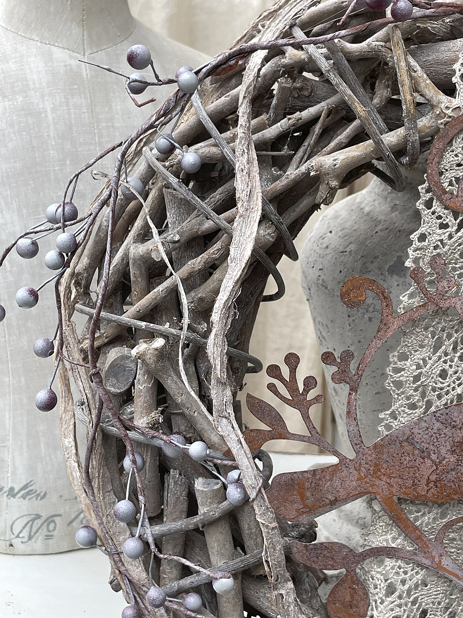 Dekorativer Kranz aus Naturmaterialien mit Beeren und Metallmotiv Natürlicher Kranz dekoriert mit Beeren und einem rustikalen Metallornament