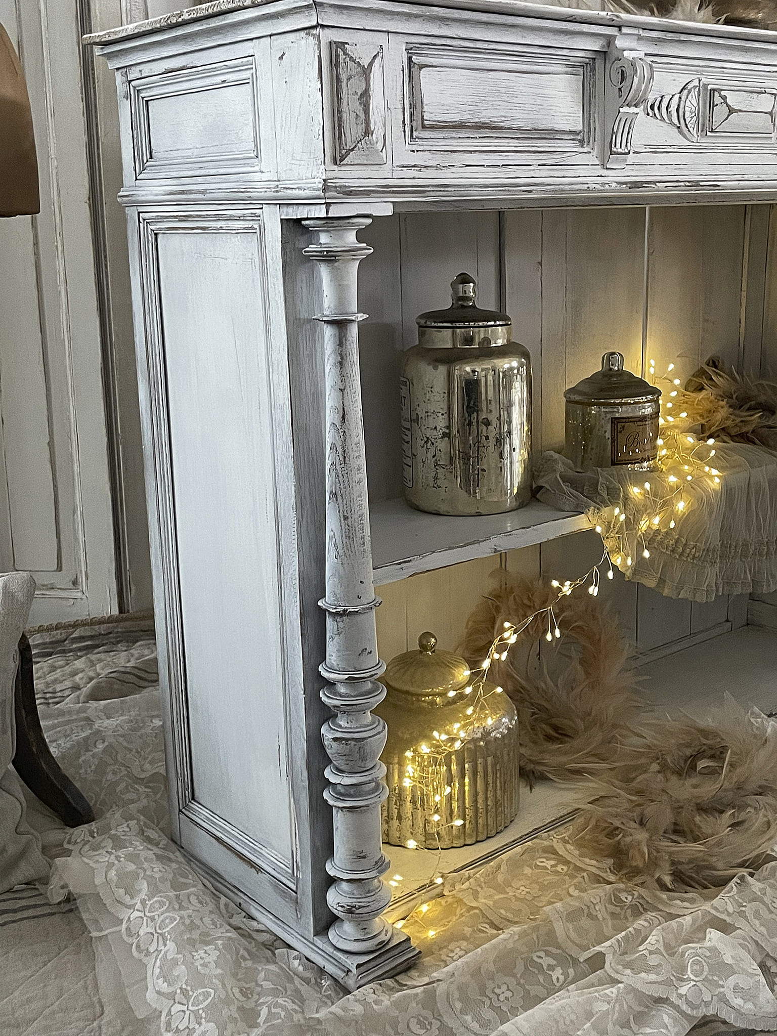 Eleganter Sideboard mit Vintage-Charme und dekorativen Elementen Detailaufnahme eines stilvollen Sideboards mit goldenen Dekorationsgegenständen und Lichterkette