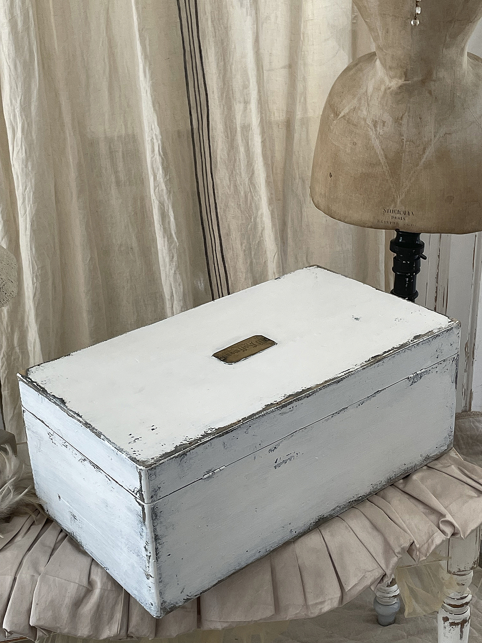 Vintage weiße Holzkiste mit Patina Eine elegante und vintage Holzkiste in Weiß, dekorativ platziert auf einem Tisch, mit einem Schaufelverschluss und patinierten Details.