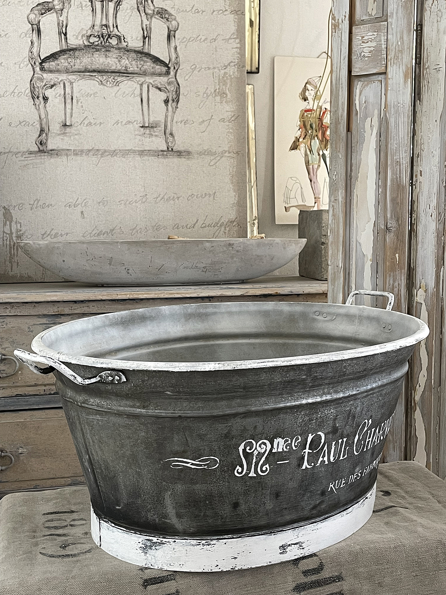 Dekorativer Eimer im Vintage-Stil mit Wasser und Aufschrift Vintage Eimer mit Wasser und französischer Aufschrift auf antikem Möbelstück