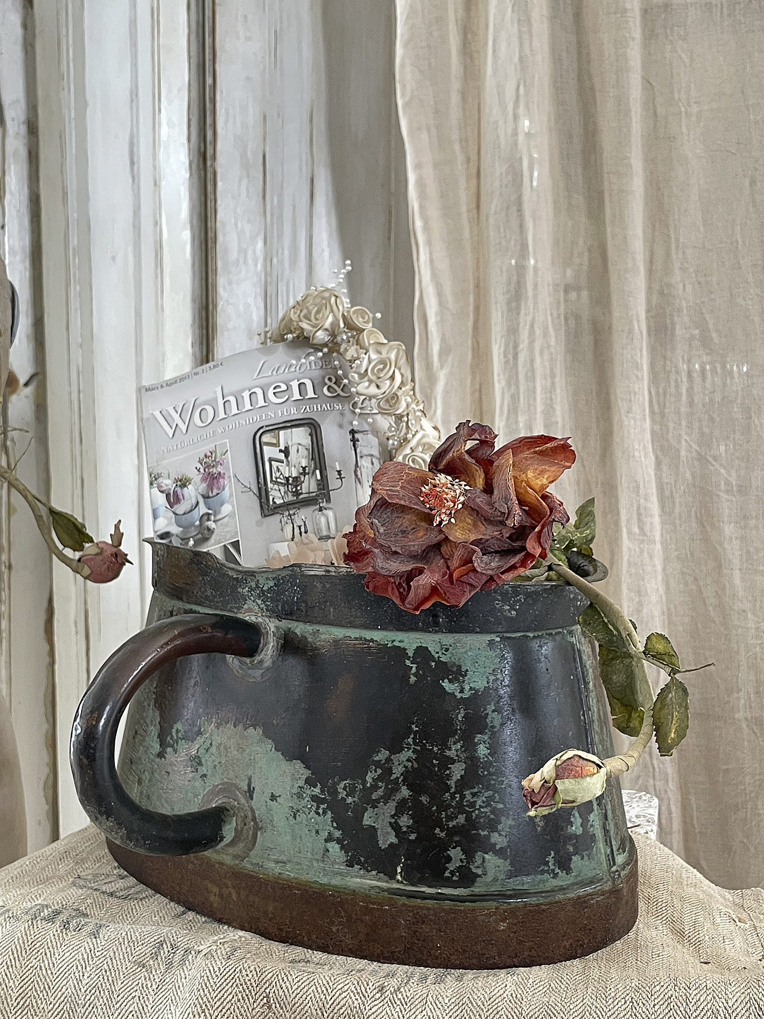 Dekoideen für Zuhause: Vintage-Tasse mit Trockenblumen und Magazinen Antike Tasse mit blühenden Trockenblumen und Wohnmagazinen als stilvolle Dekoration
