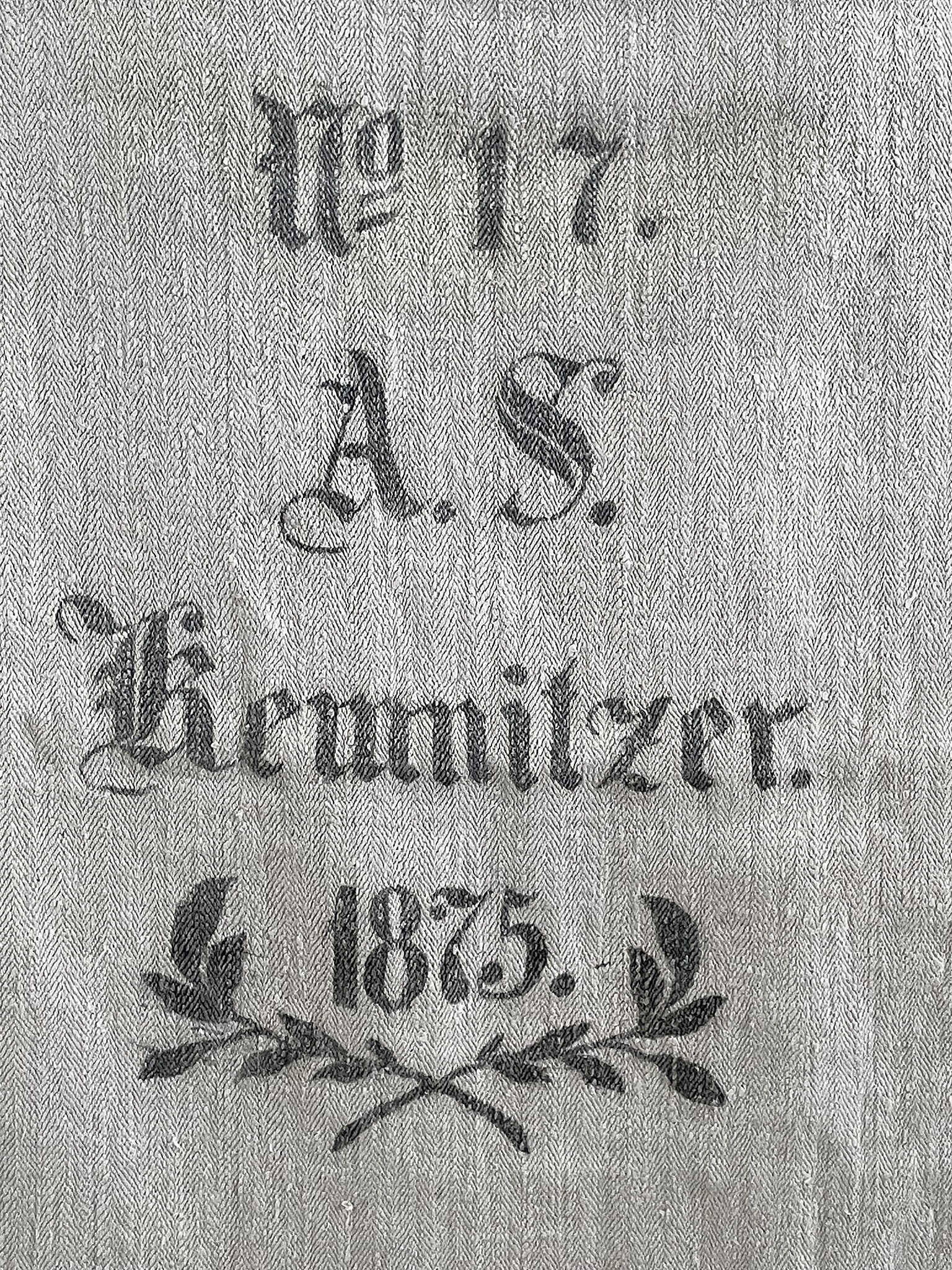 Historisches Textil mit der Aufschrift A. S. Kewniltzer, 1875 Detail eines historischen Textils mit der Beschriftung A. S. Kewniltzer und dem Jahr 1875