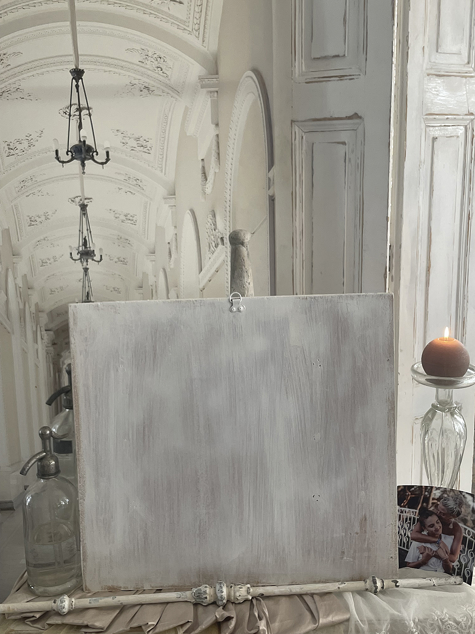 Leeres Schild mit dekorativen Accessoires in elegantem Raum Dekoratives Arrangement mit leeren Holzschild, Kerze und Glasflasche in stilvollem Innenraum