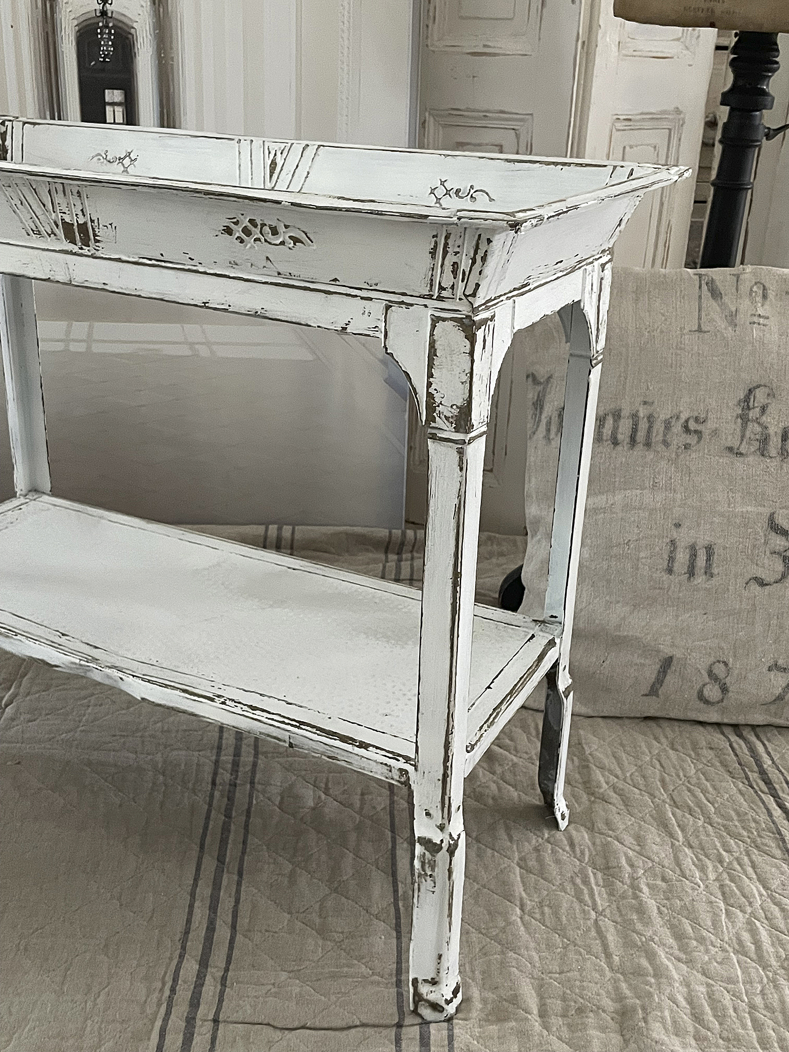 Beistelltisch im Shabby-Chic-Stil mit geschliffener weißer Oberfläche und dekorativen Details.
