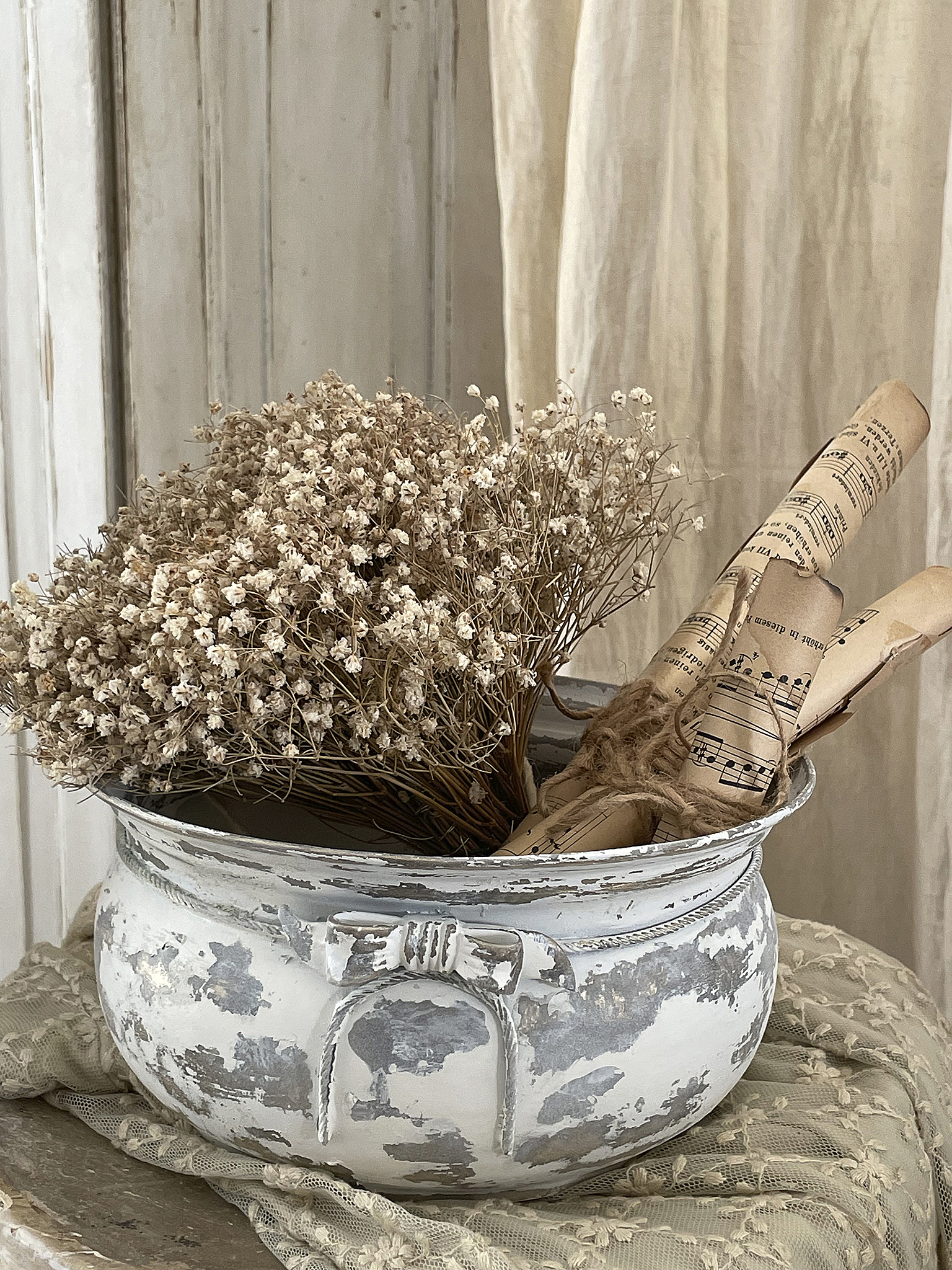 Rustikaler Blumentopf mit getrockneten Blumen und Notenrollen Eleganter Blumentopf mit braunen getrockneten Blumen und alten Notenrollen auf einem Tisch