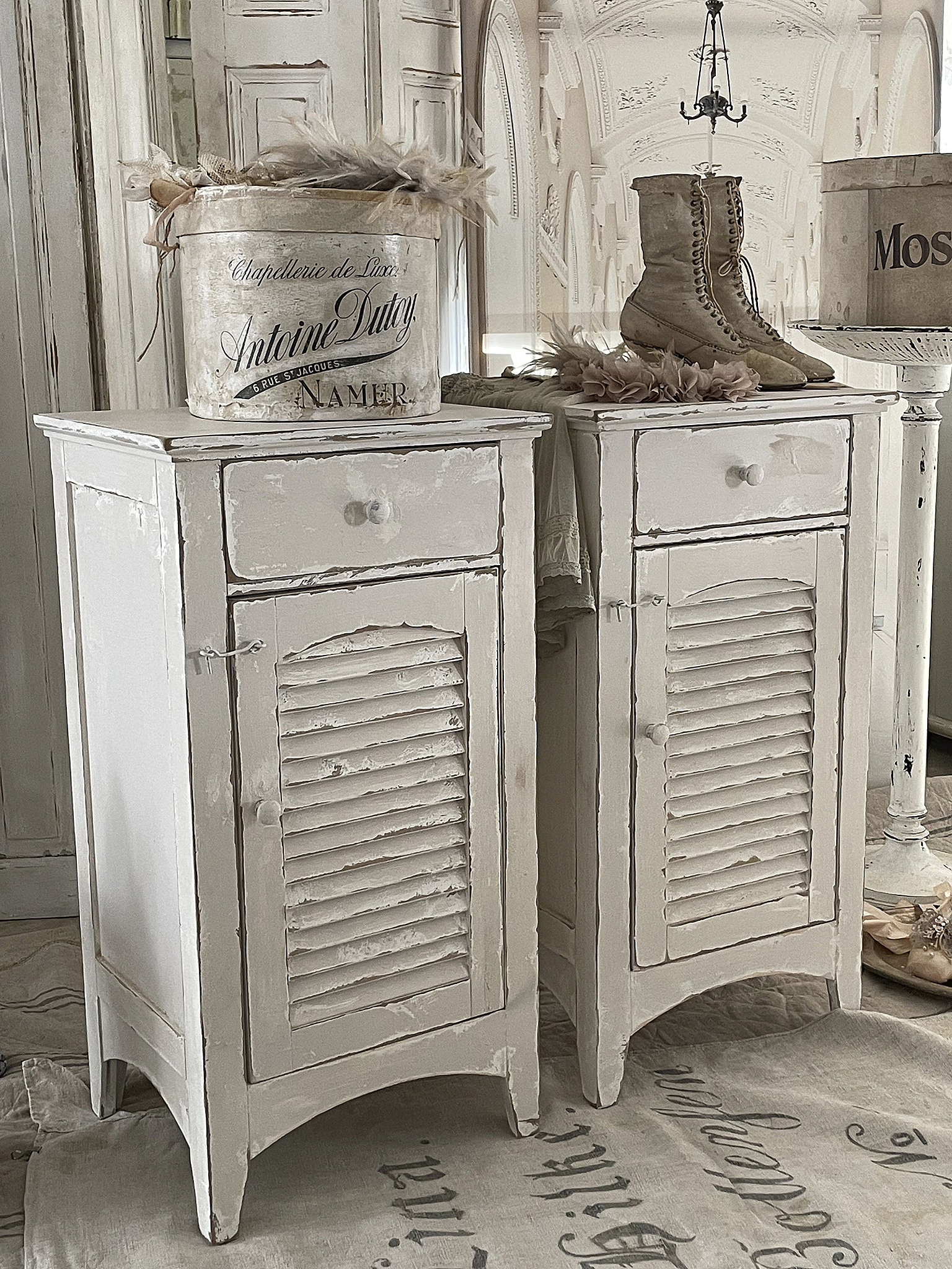 Weißes Vintage-Nachtkästchen-Set mit dekorativen Details Zwei weiße Vintage-Nachtkästchen mit Schubladen und dekorativen Elementen in einer stilvollen Inneneinrichtung