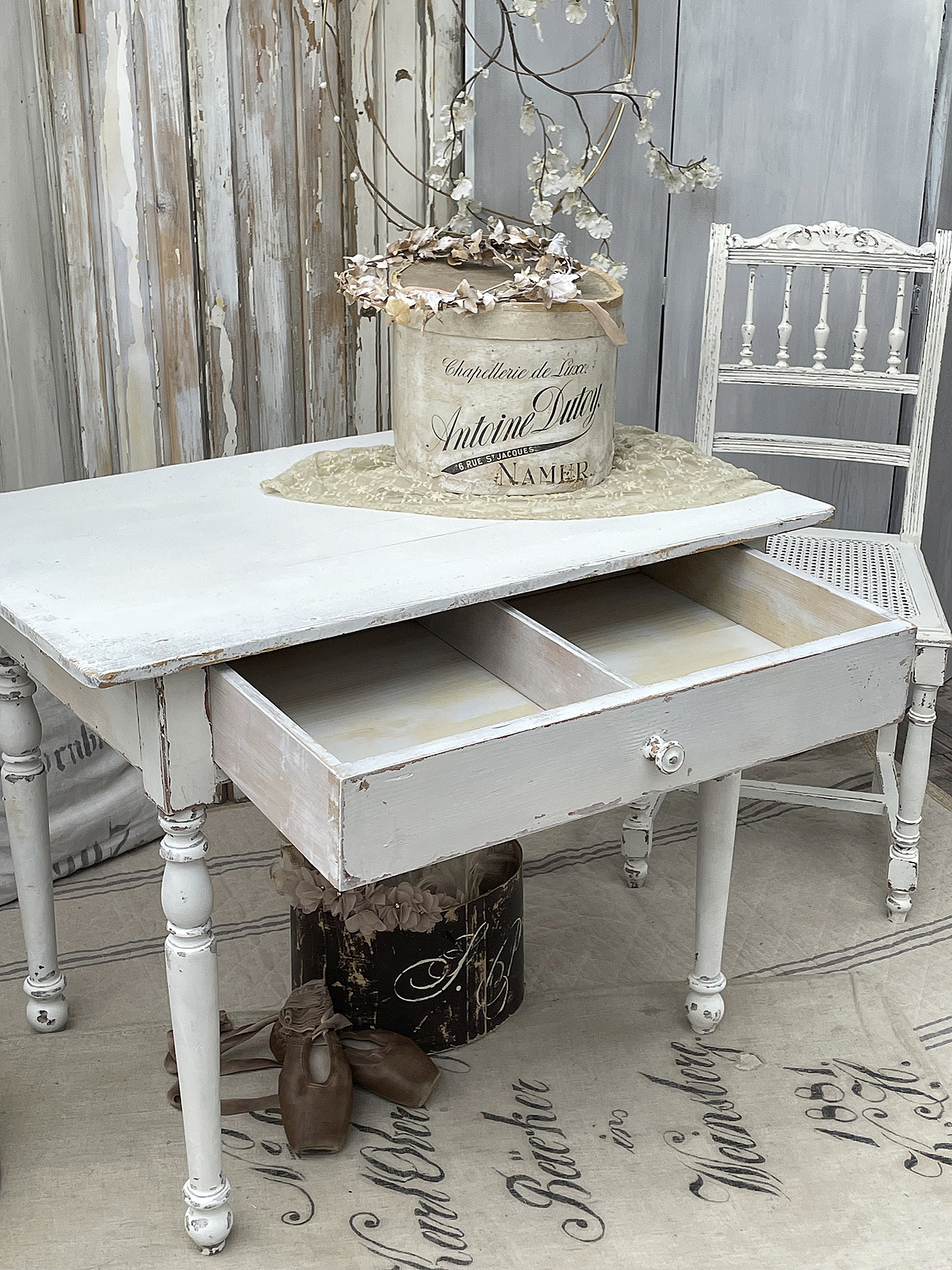 Eleganter shabby-chic Schreibtisch mit Schubladen und Dekoration Weißer shabby-chic Schreibtisch mit offenen Schubladen, daneben eine stilvolle Dekoration