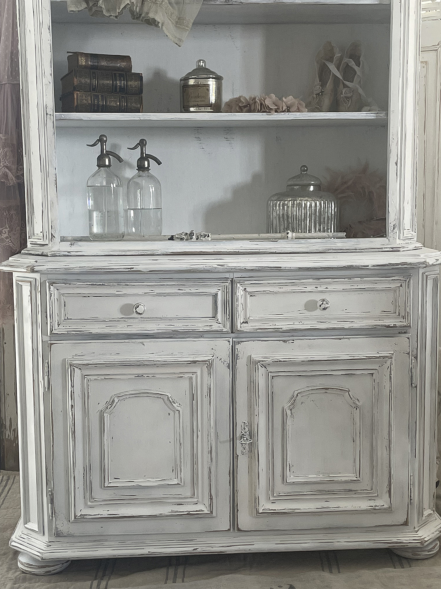Vintage weißer Schrank mit Glasbehältern und dekorativen Elementen Detailaufnahme eines antiken weißen Schranks mit Glasbehältern, Büchern und Dekoration