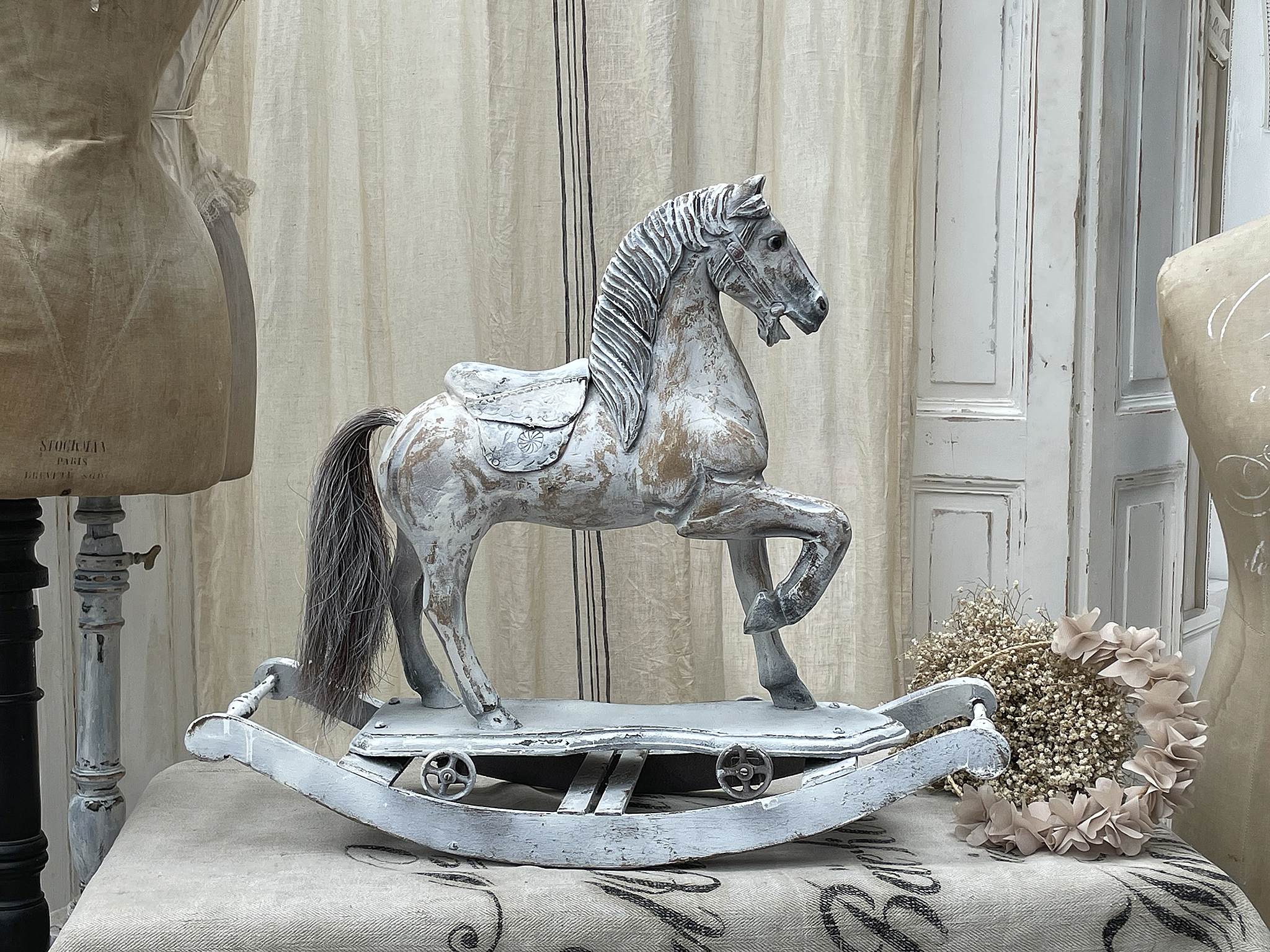 Holzschaukelpferd auf einem Tisch im Innenraum mit dekorativen Elementen.