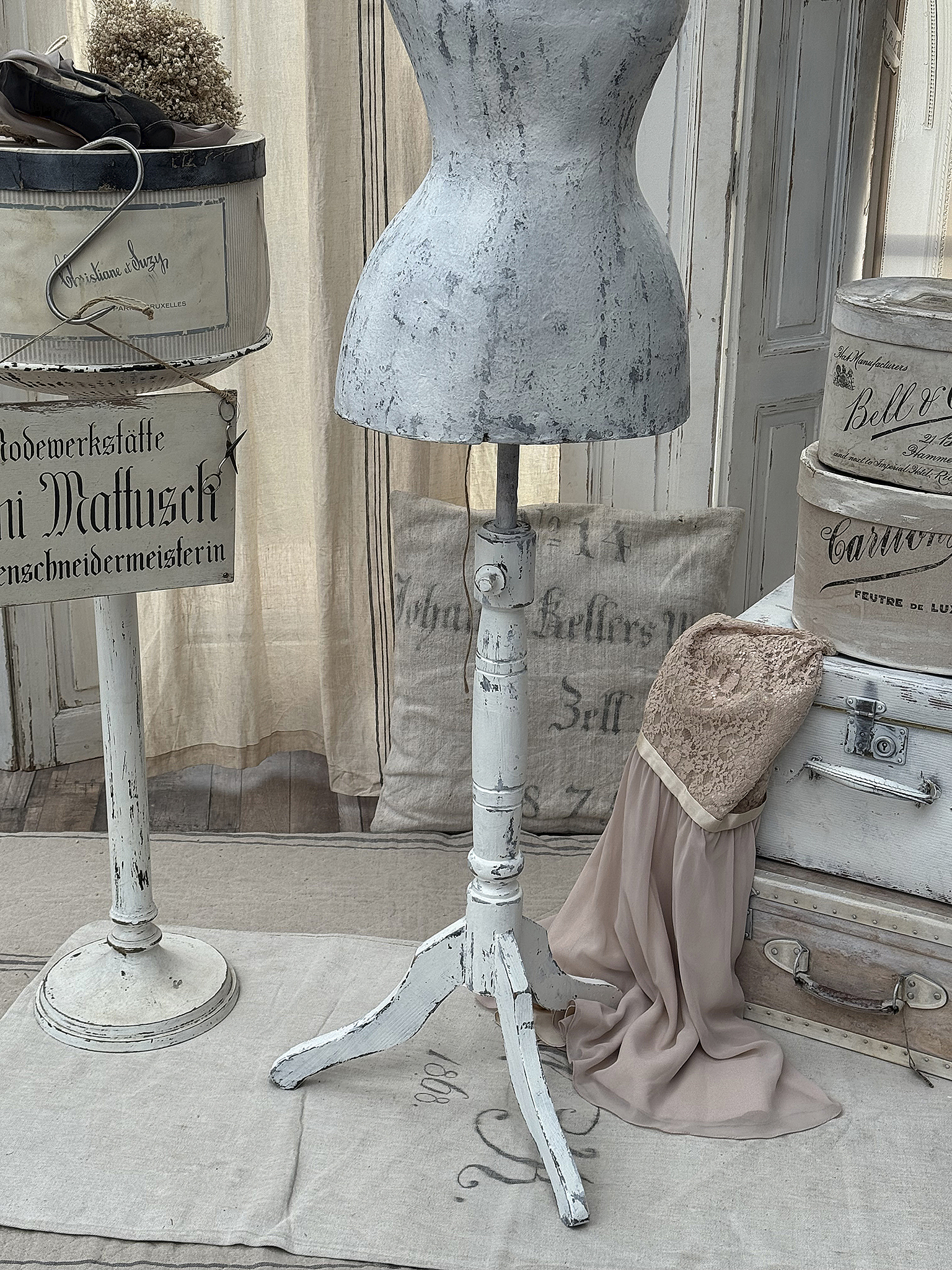 Vintage Schneiderpuppe aus weißem Holz mit dekorativen Stoffen und antiken Kisten