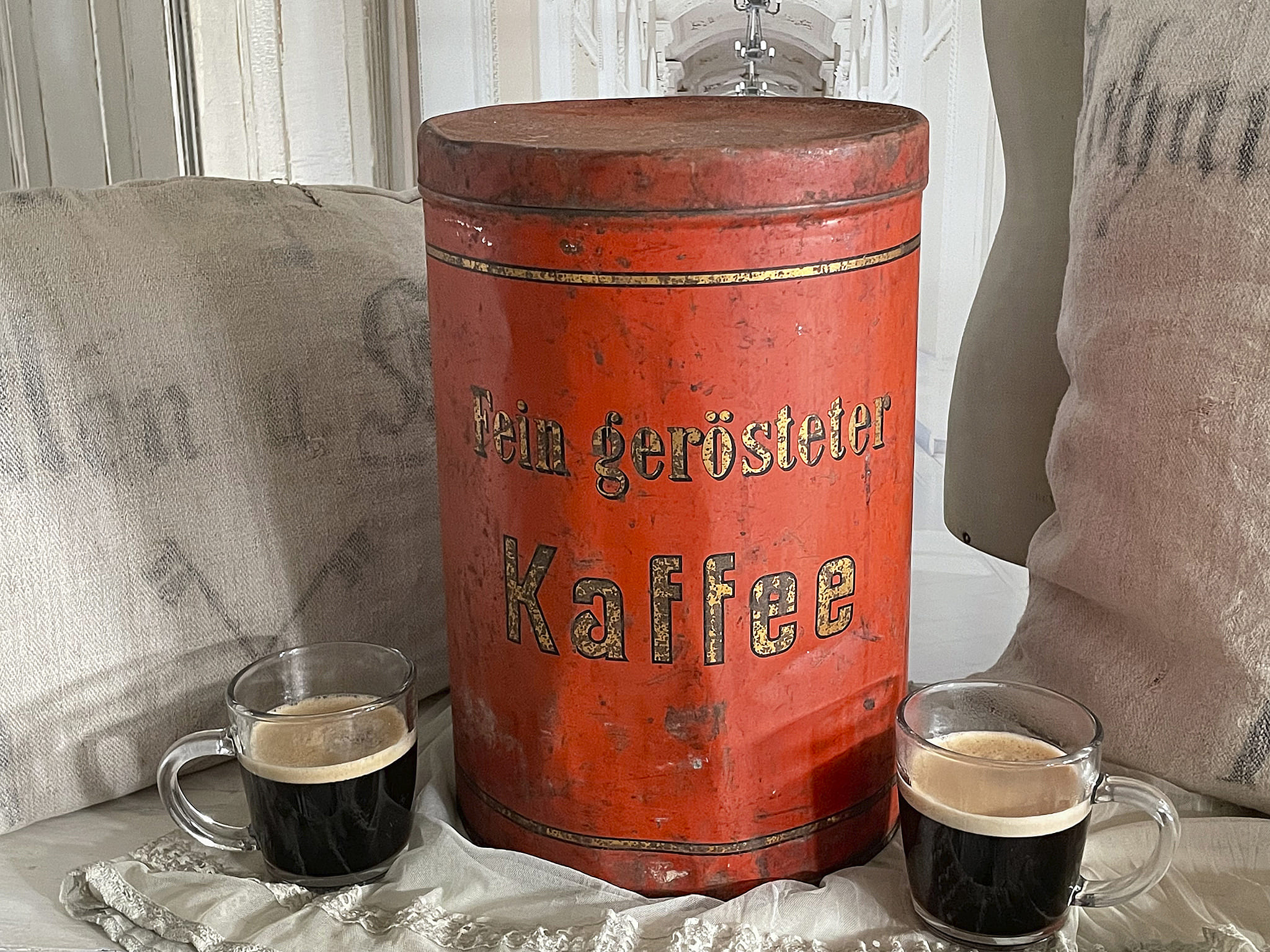 Alte Kaffeebehälter aus Blech mit zwei Kaffeetassen auf einem Tisch