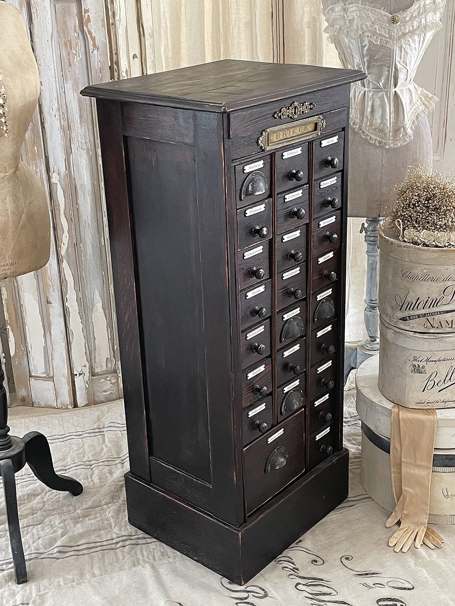 Eindrucksvoller antiker Schrank mit zahlreichen Schubladen zur Aufbewahrung, umgeben von nostalgischen Accessoires.