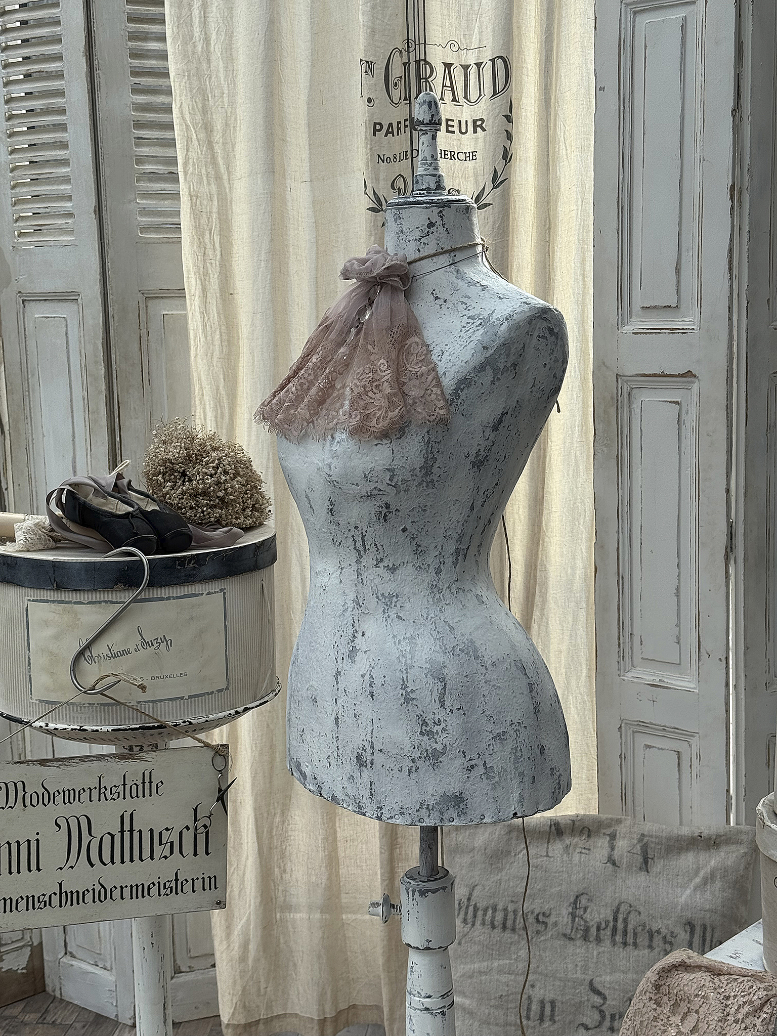Schneiderpuppe mit rosa Spitzenschal und vintage Dekor im Hintergrund