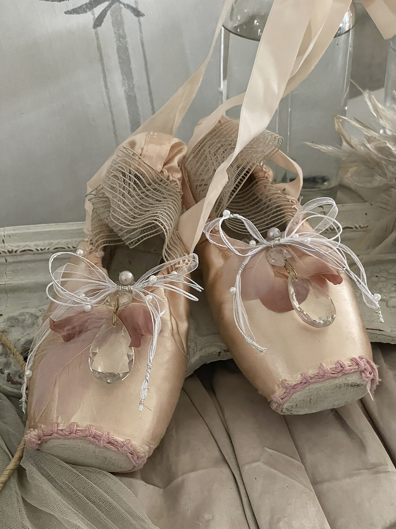 Zwei elegante Ballettschuhe in sanften Farben, verziert mit Perlen und einer transparenten Dekoration.