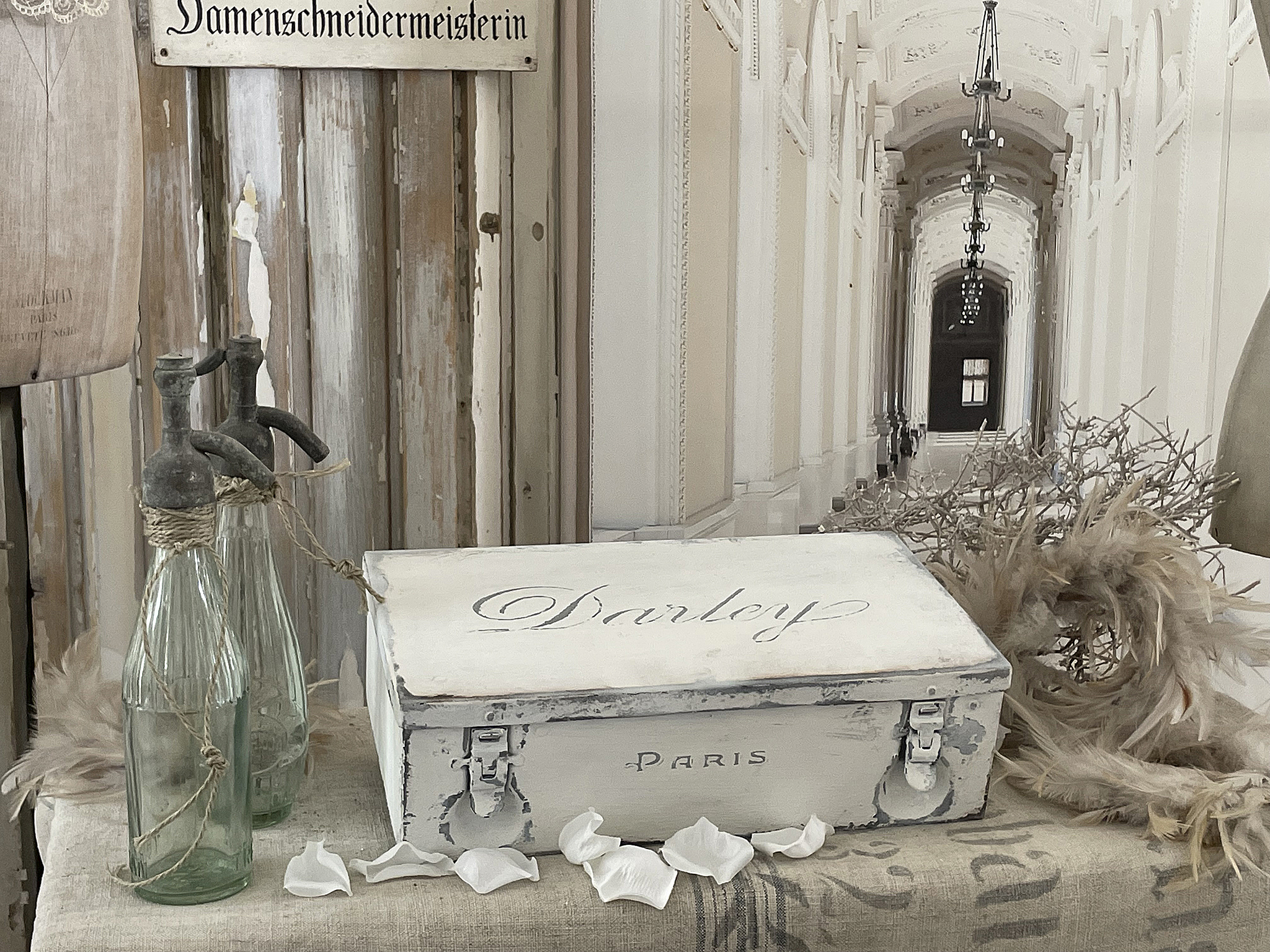 Vintage Dekorationselemente mit Paris Schriftzug und Glasflaschen Dekoration im Vintage-Stil mit einer Truhe und Glasspritzern in einem eleganten Innenraum