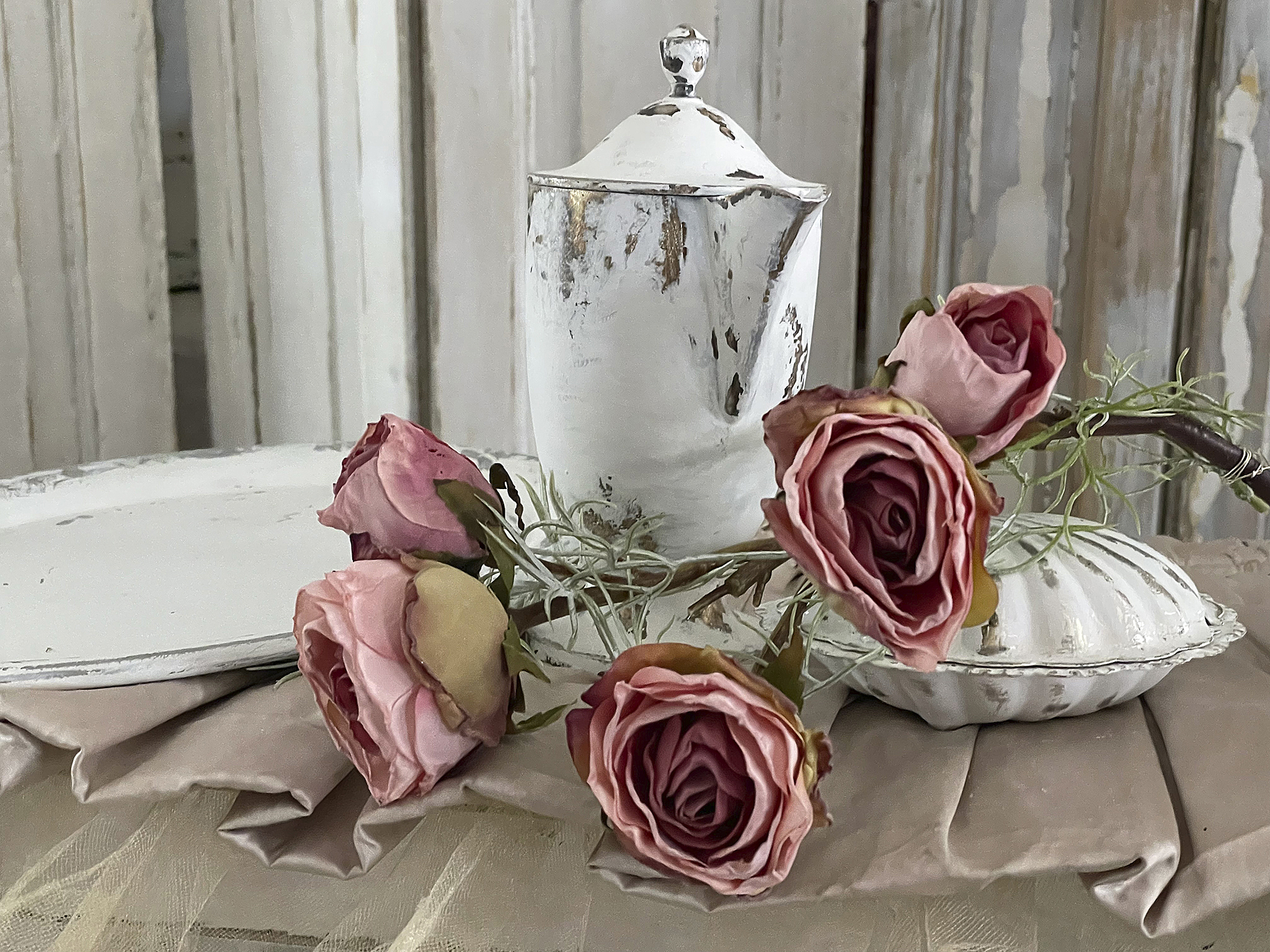 Teekanne aus weißem Porzellan mit rosa Rosen auf einem gedeckten Tisch