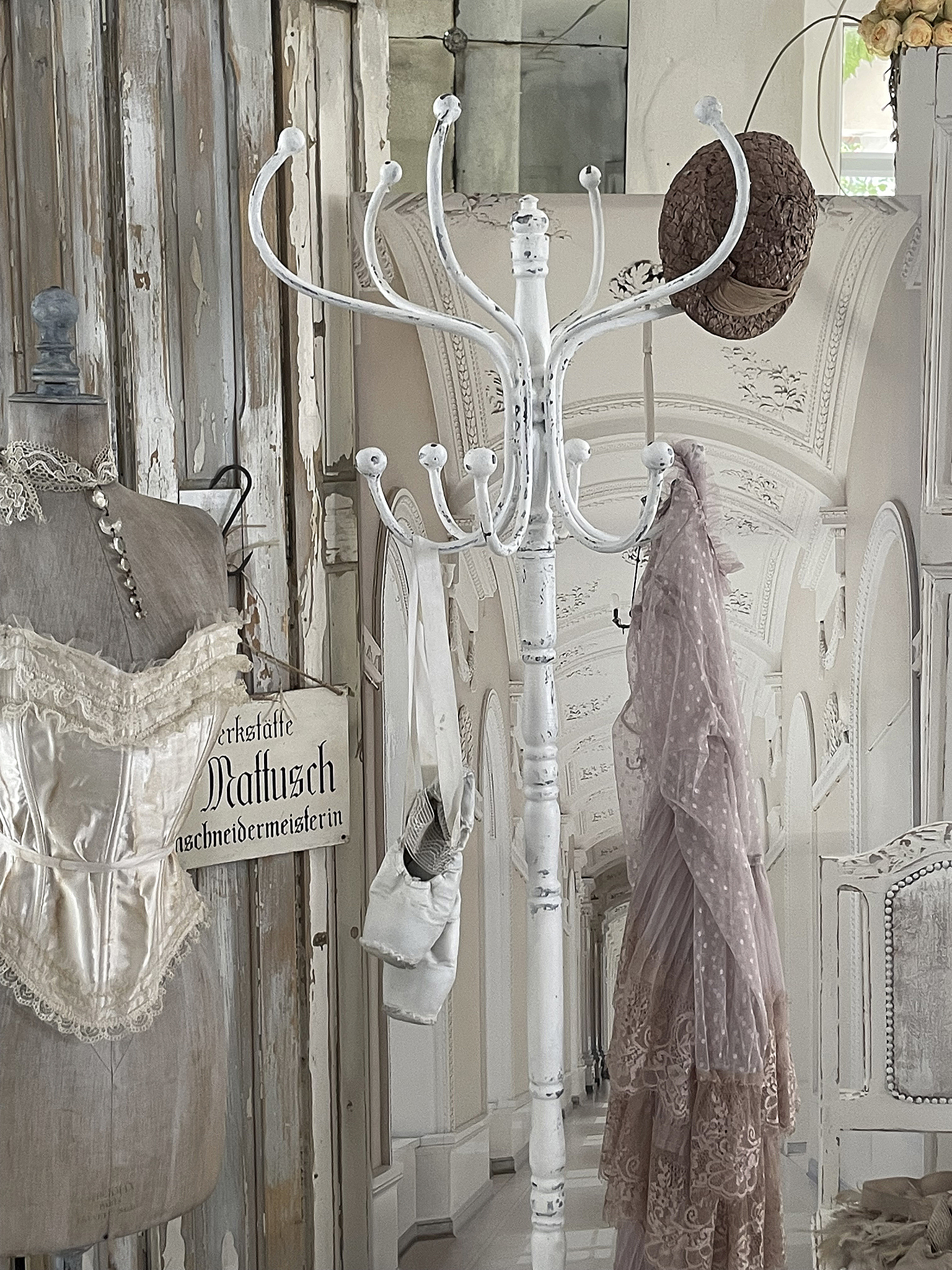 Kleiderständer mit Hüte und Kleidern im vintage Stil Eleganter Kleiderständer mit Hut und zarten Kleidern in einem stilvollen Raum