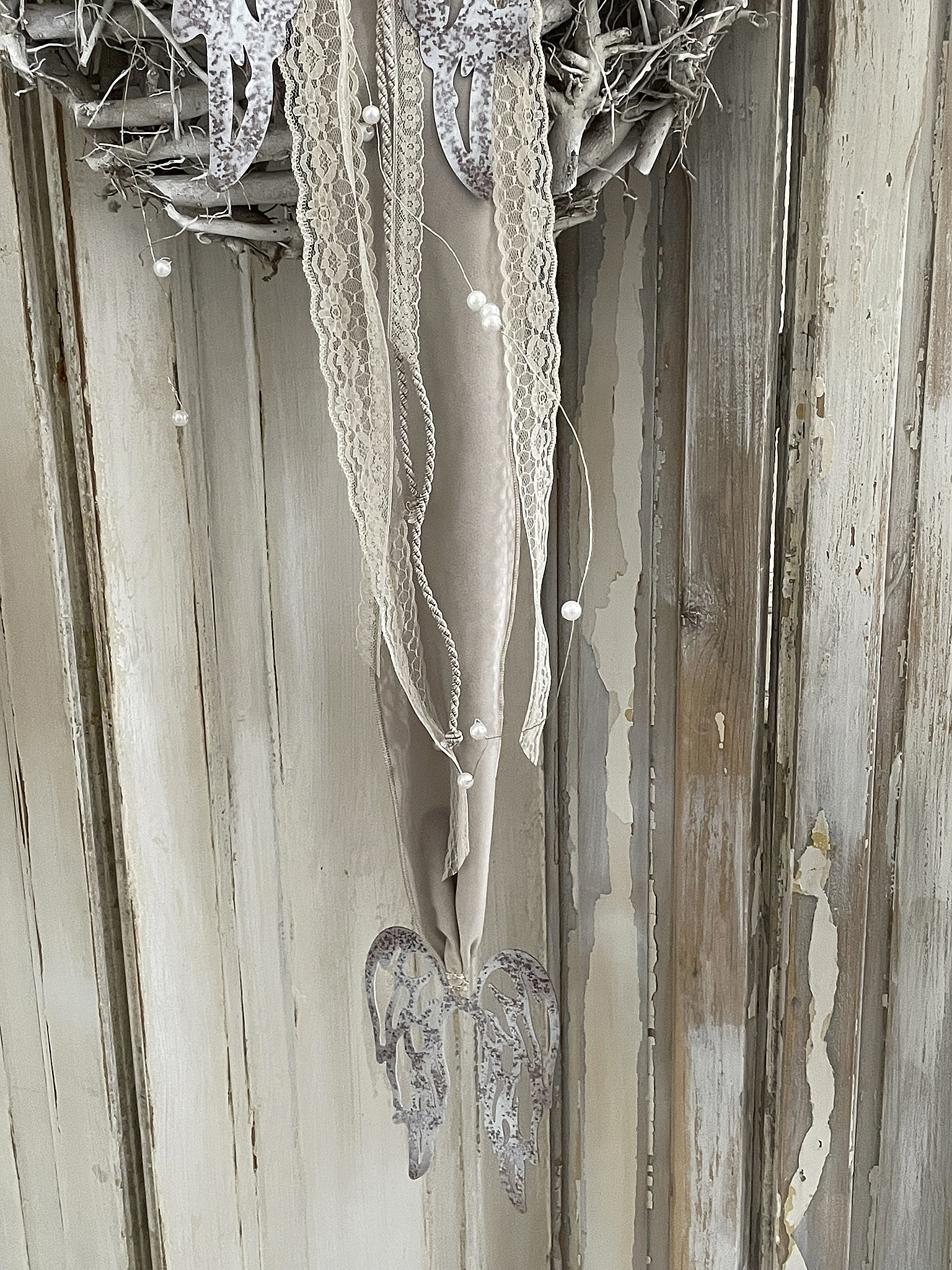 Detailaufnahme eines Wandanhängers mit Engel-Flügeln und dekorativen Bändern