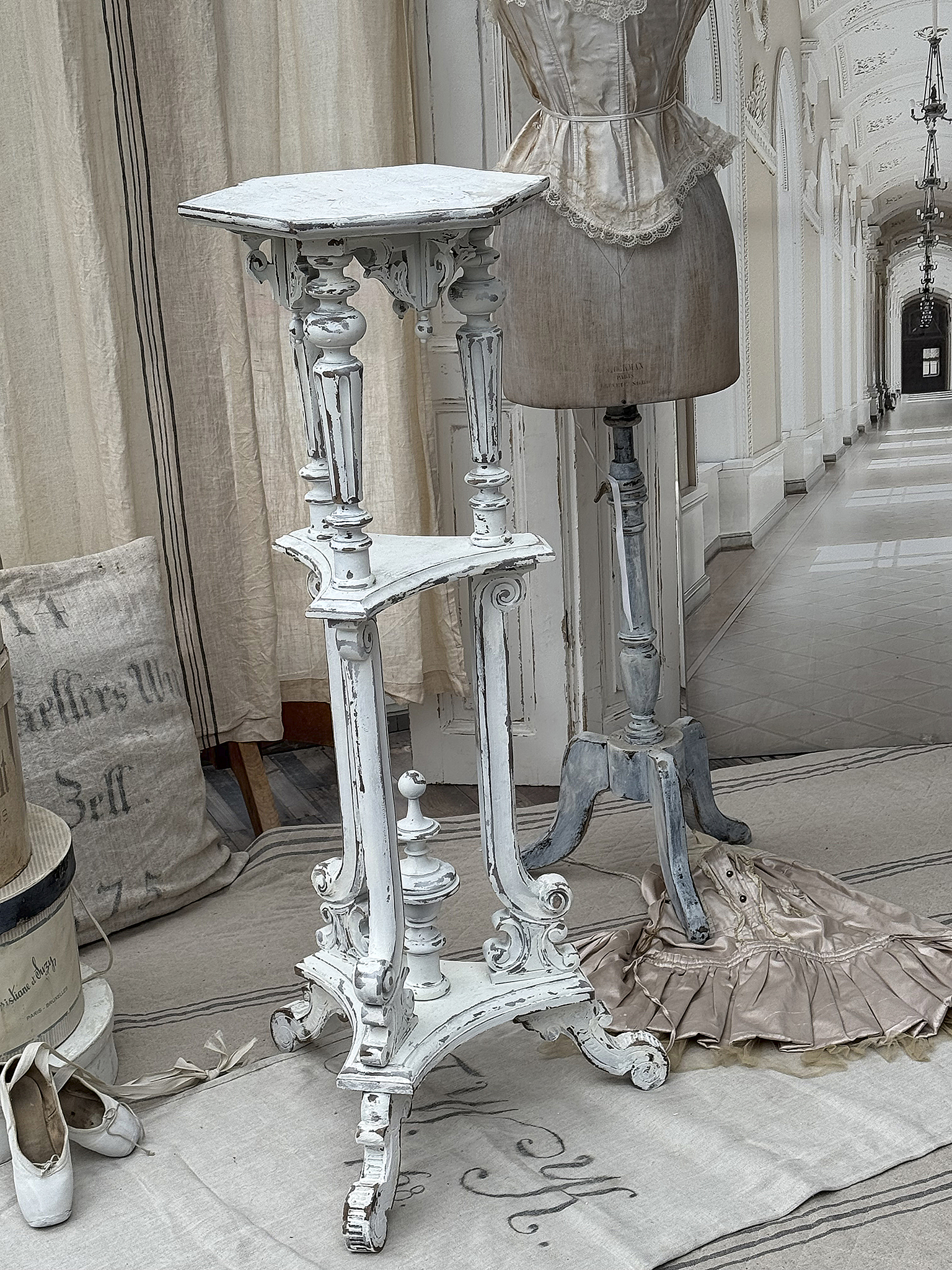 Eleganter antiker Beistelltisch im Shabby-Chic-Stil Antiker Beistelltisch aus Holz im Shabby-Chic mit kleinem Kissen und Schneiderpuppe im Hintergrund