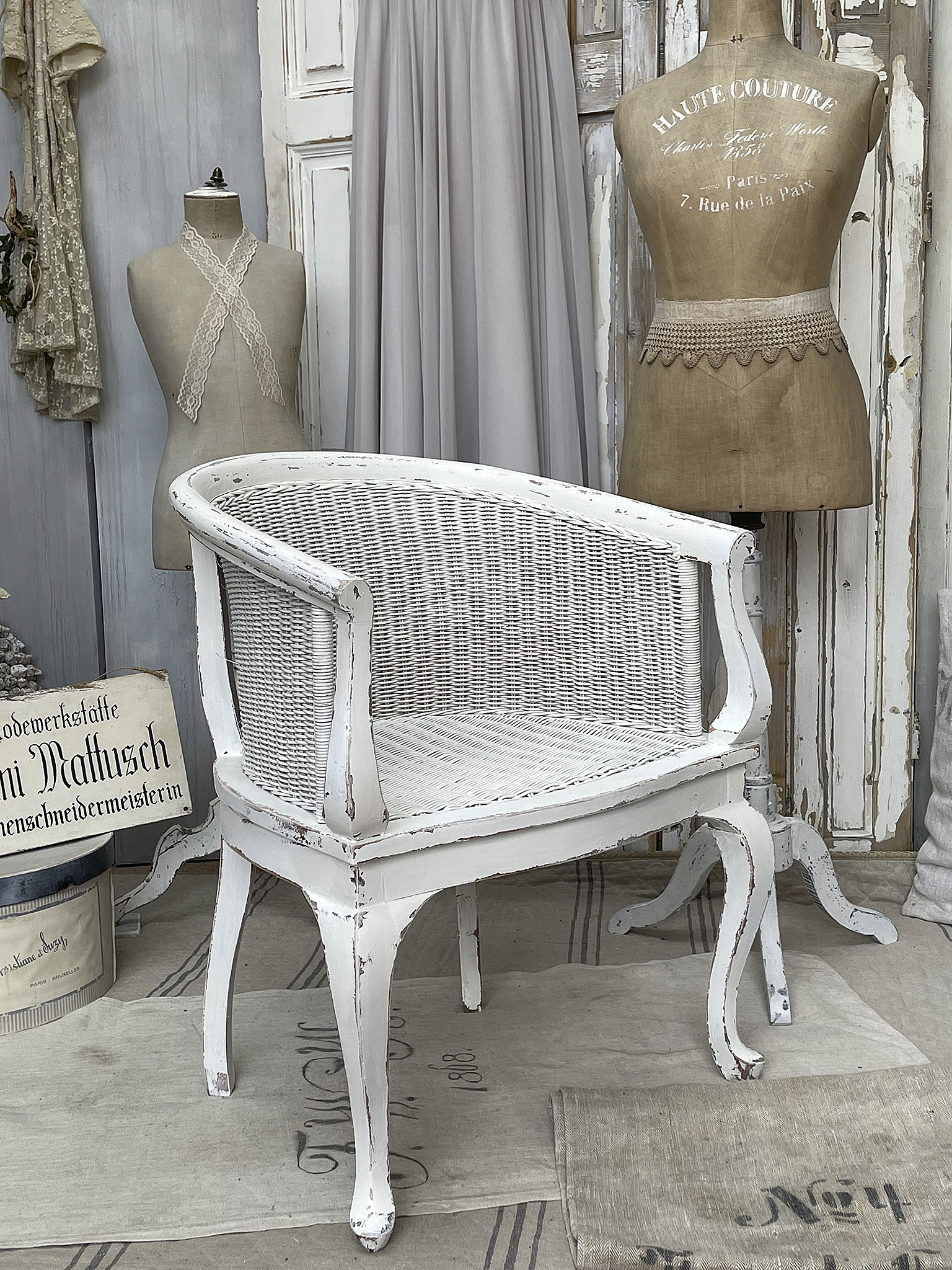 Weißer Korbstuhl im Vintage-Stil Eleganter weißer Korbstuhl mit leicht abgenutzter Oberfläche, ideal für stilvolle Inneneinrichtungen.