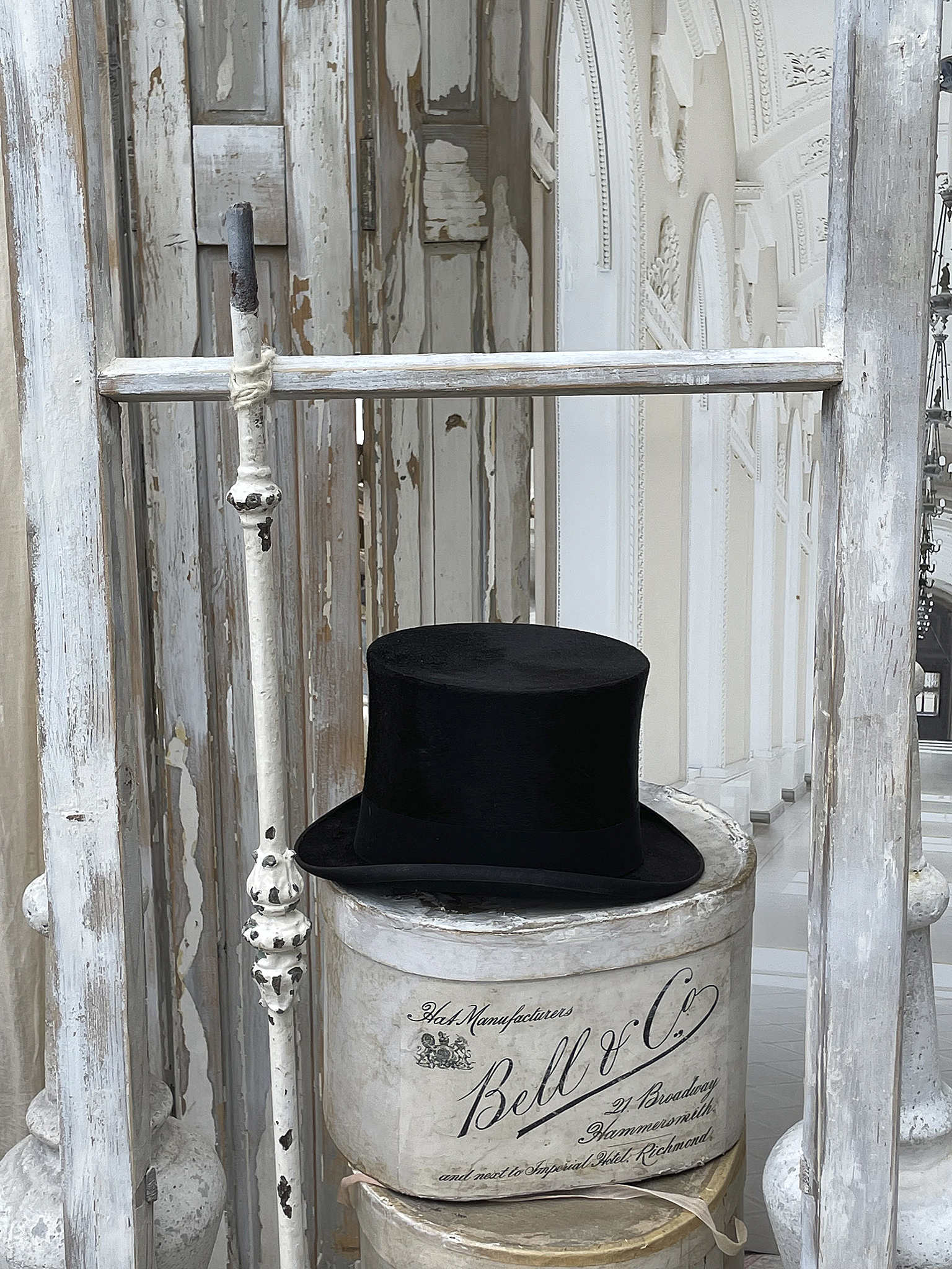 Schwarzer Zylinder auf einem antiken Behälter Eleganter schwarzer Zylinderhut auf einem vintage Behälter, dekorativer Hintergrund.