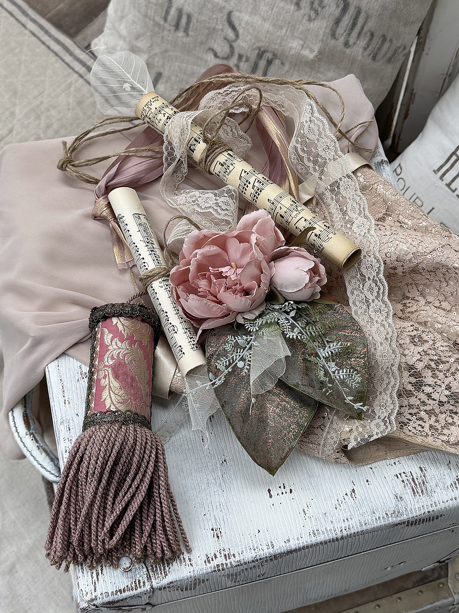 Dekorative Vintage-Dekoration mit Blüten und Notenrollen Schöne Vintage-Dekoration mit rosa Blüten, Notenrollen und Spitze auf einem weißen Holzuntergrund