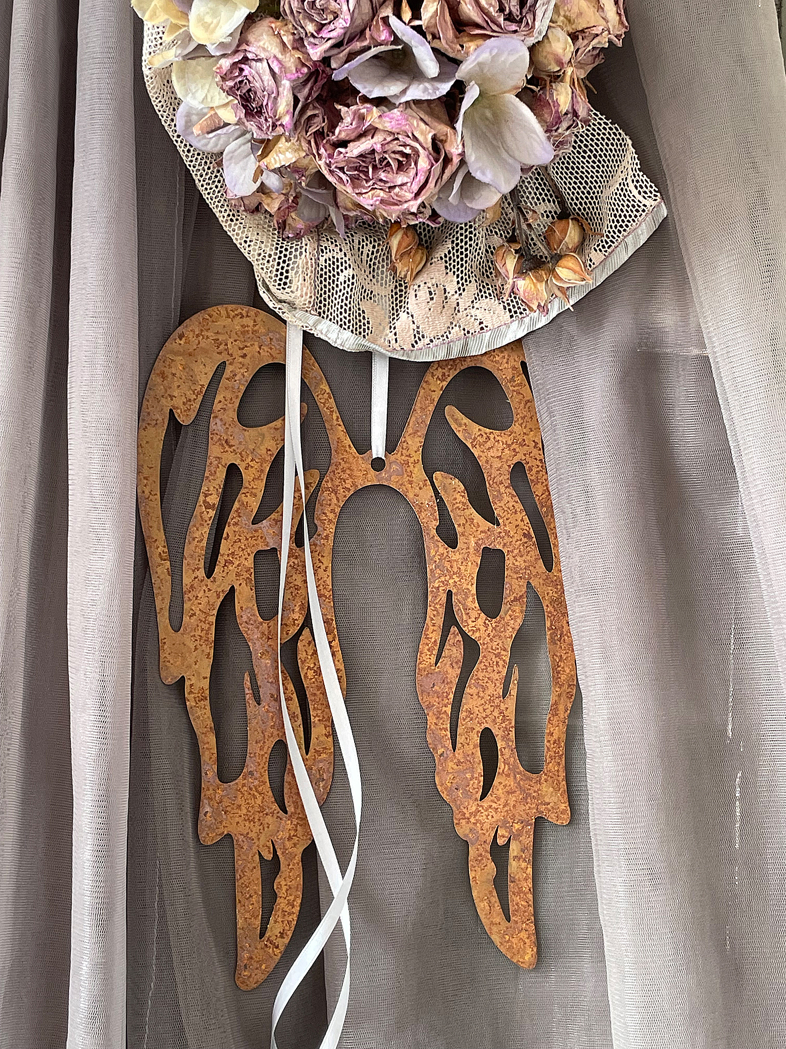 Dekorative Metallflügel mit Blumenarrangement Schöne Metallflügel hängen dekorativ mit einem Blumenarrangement aus getrockneten Rosen und Hyazinthen.