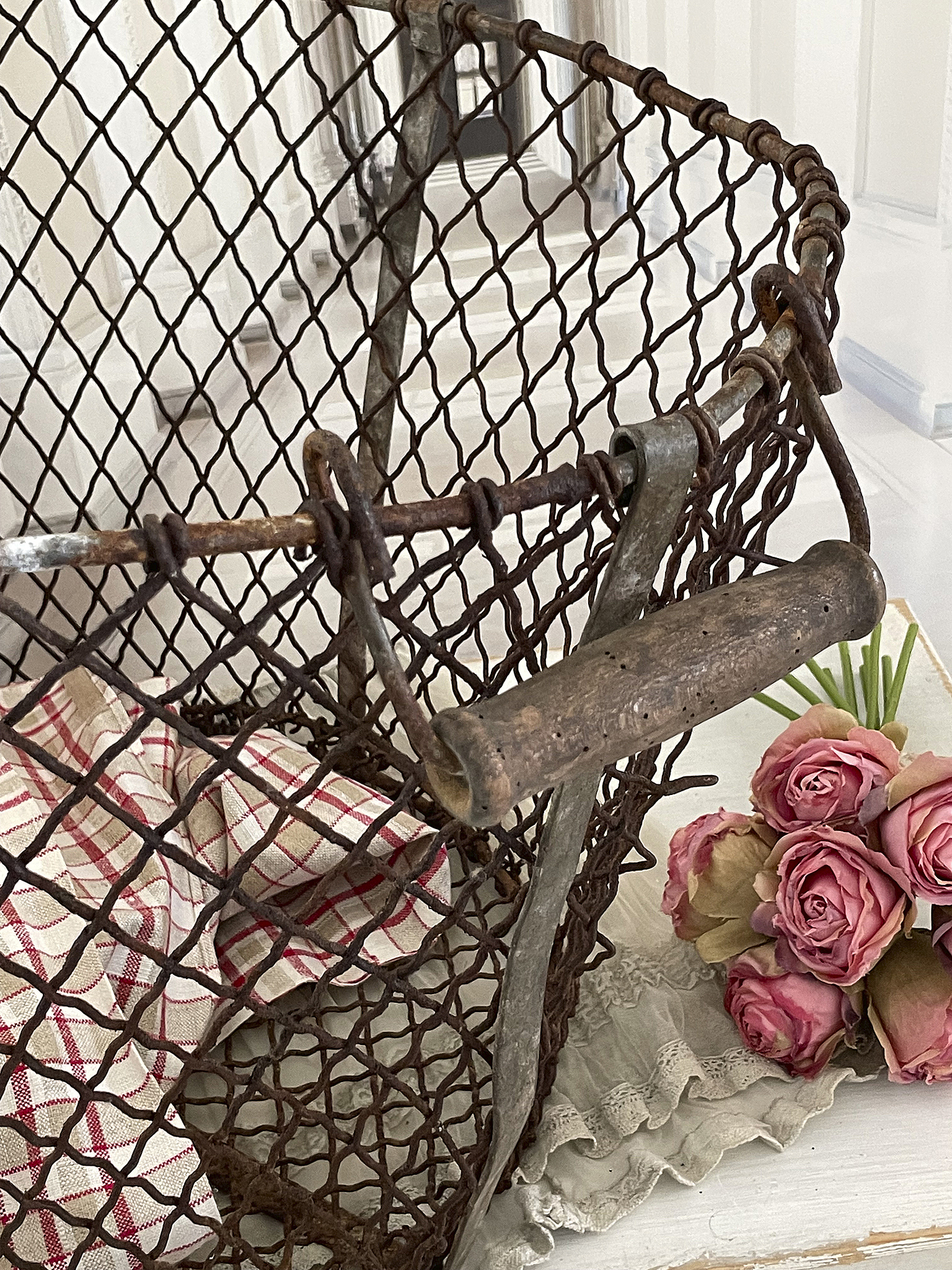 Retro Drahtkorb mit Rosen und Tuch für eine romantische Dekoration Antiker Drahtkorb mit Holzgriff und rosa Rosen auf einem Tisch, ideal für Dekorationsideen