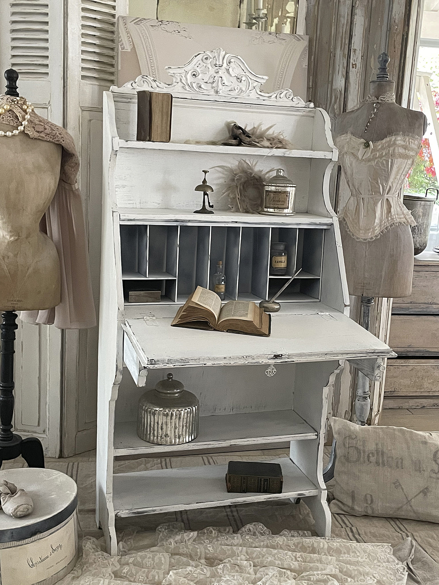 Eleganter Vintage-Schreibtisch mit dekorativen Accessoires Vintage-Schreibtisch in Weiß mit einem offenen Buch und stilvollen Deko-Elementen