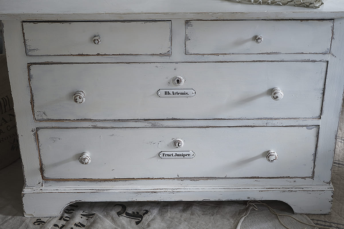 Elegante Kommode mit mehreren Schubladen in Weiß Detailansicht einer weißen Kommode mit drei Schubladen und nostalgischen Griffen.