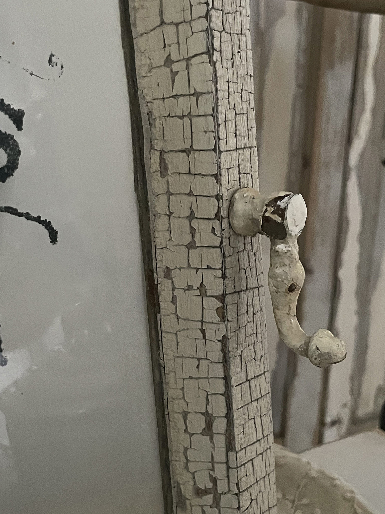 Detailaufnahme eines antiken Garderobenhakens an einer Wand mit sichtbarer Rissbildung