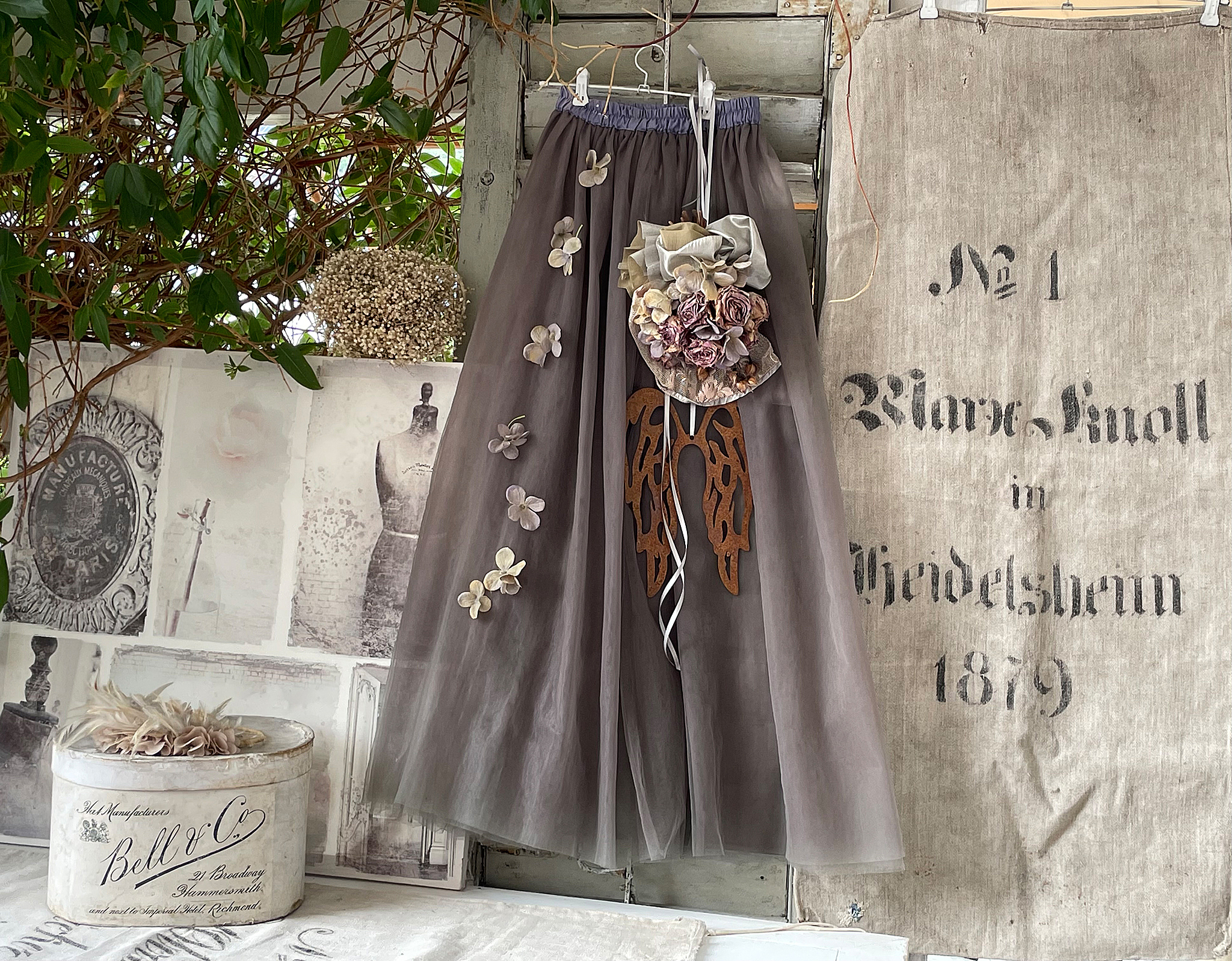 Eleganter grauer Rock mit Blumenapplikationen und dekorativem Detail Grauer Tüllrock mit floralen Applikationen und einem kunstvollen Clip aus Stoffblumen.