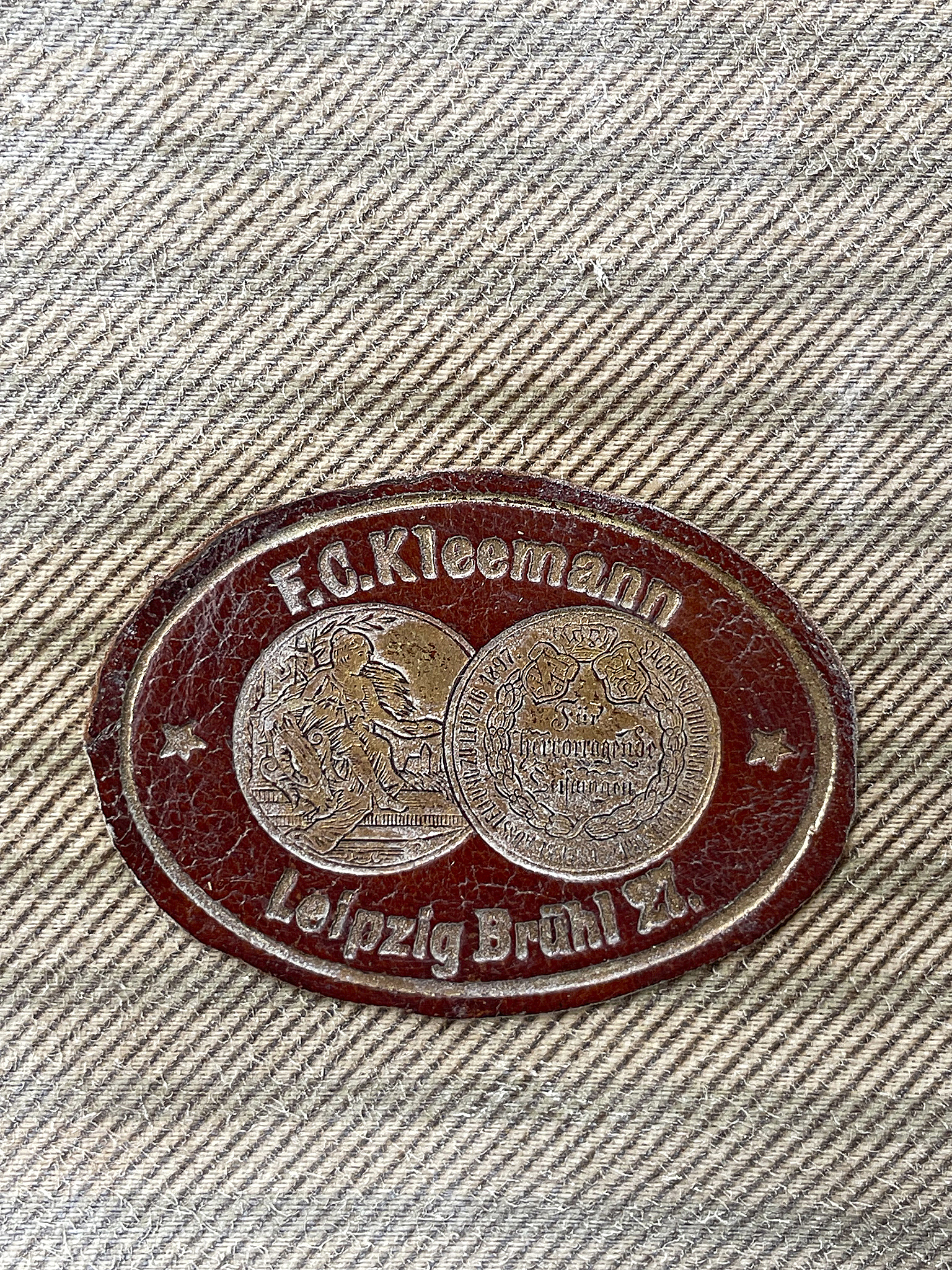Emblem von F. C. Kleemann aus Leipzig Brühl Z. Vintage Emblem von F. C. Kleemann, Leipzig Brühl Z., auf Stoffhintergrund.