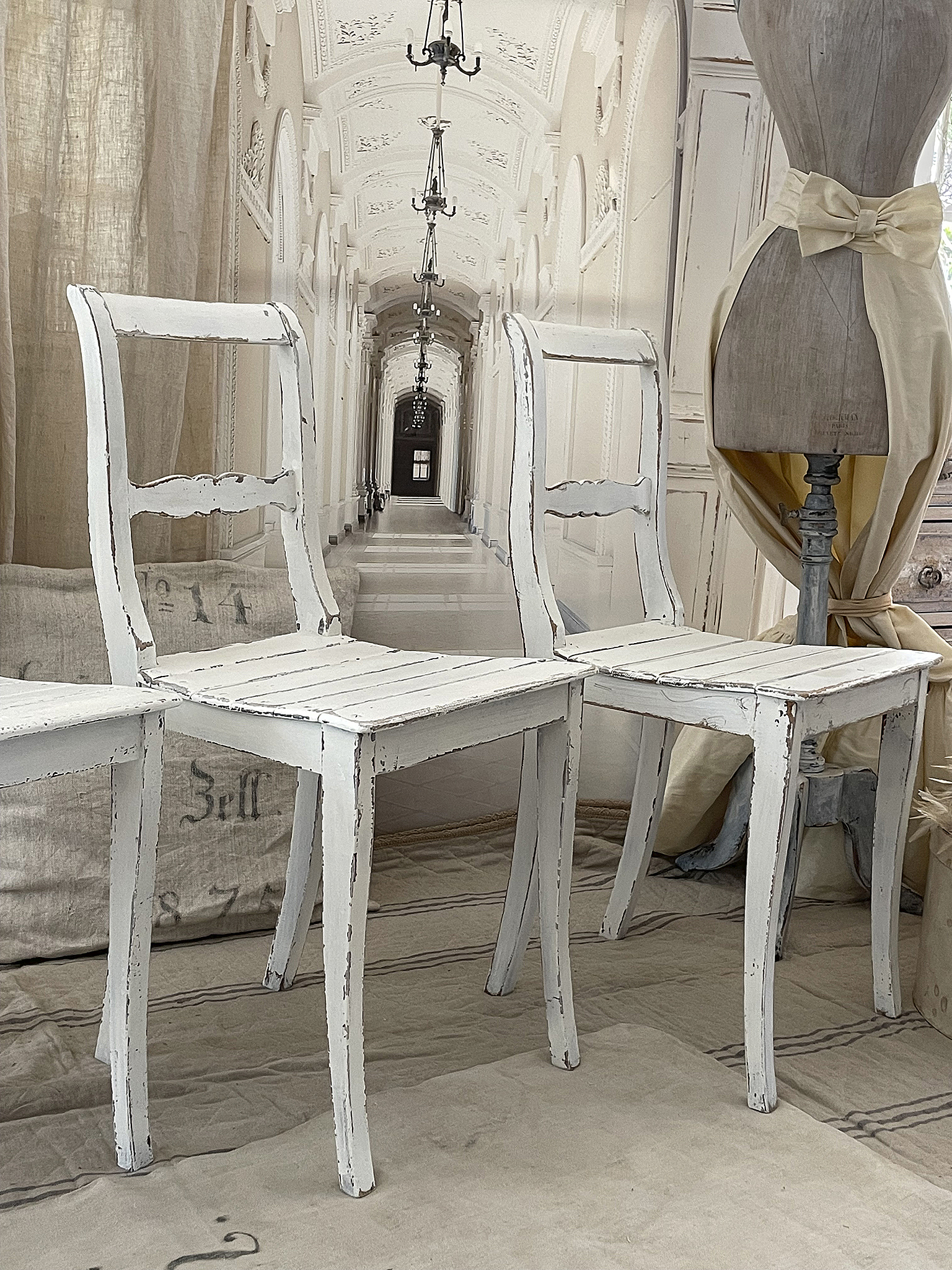 Rustikale weiße Stühle für ein stilvolles Ambiente Drei vintage weiße Stühle in einem eleganten Raum mit neutralen Farben
