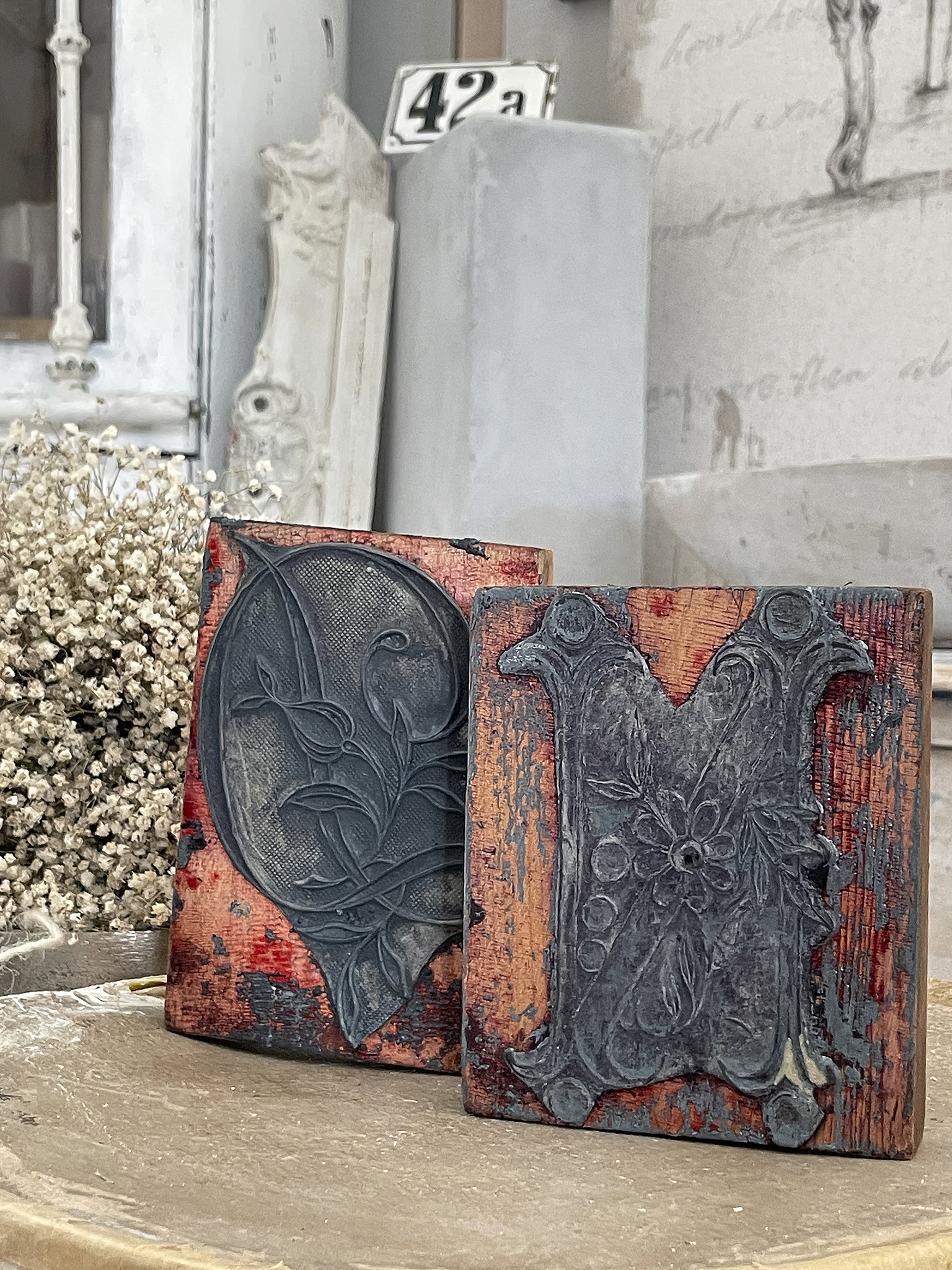 Zwei antike Druckplatten mit kunstvollen floralen Verzierungen auf Holzuntergrund.