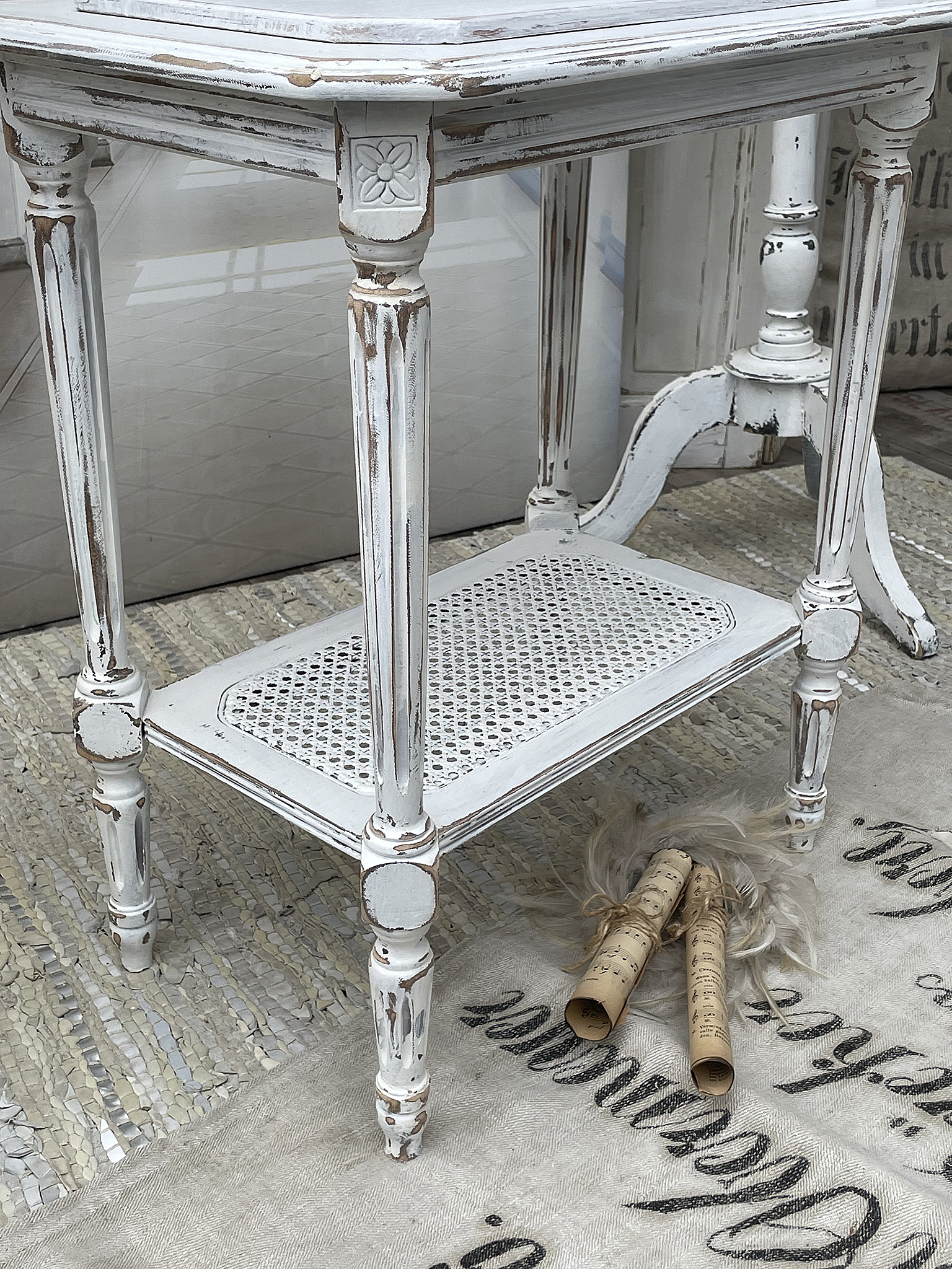 Eleganter, vintage Tisch mit verzierten Beinen und rustikalem Design Vintage Tisch mit weißer, geschwungener Oberfläche und geflochtenem Regalboden
