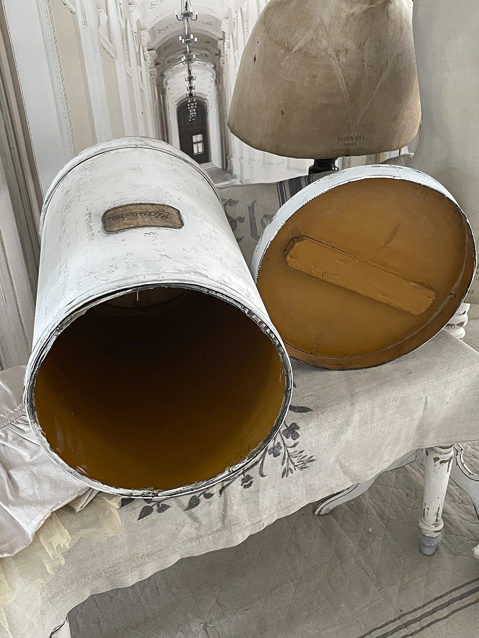 Zwei weiße Vintage Metalleimer mit leuchtend orangefarbenem Innenraum auf einem Tisch.