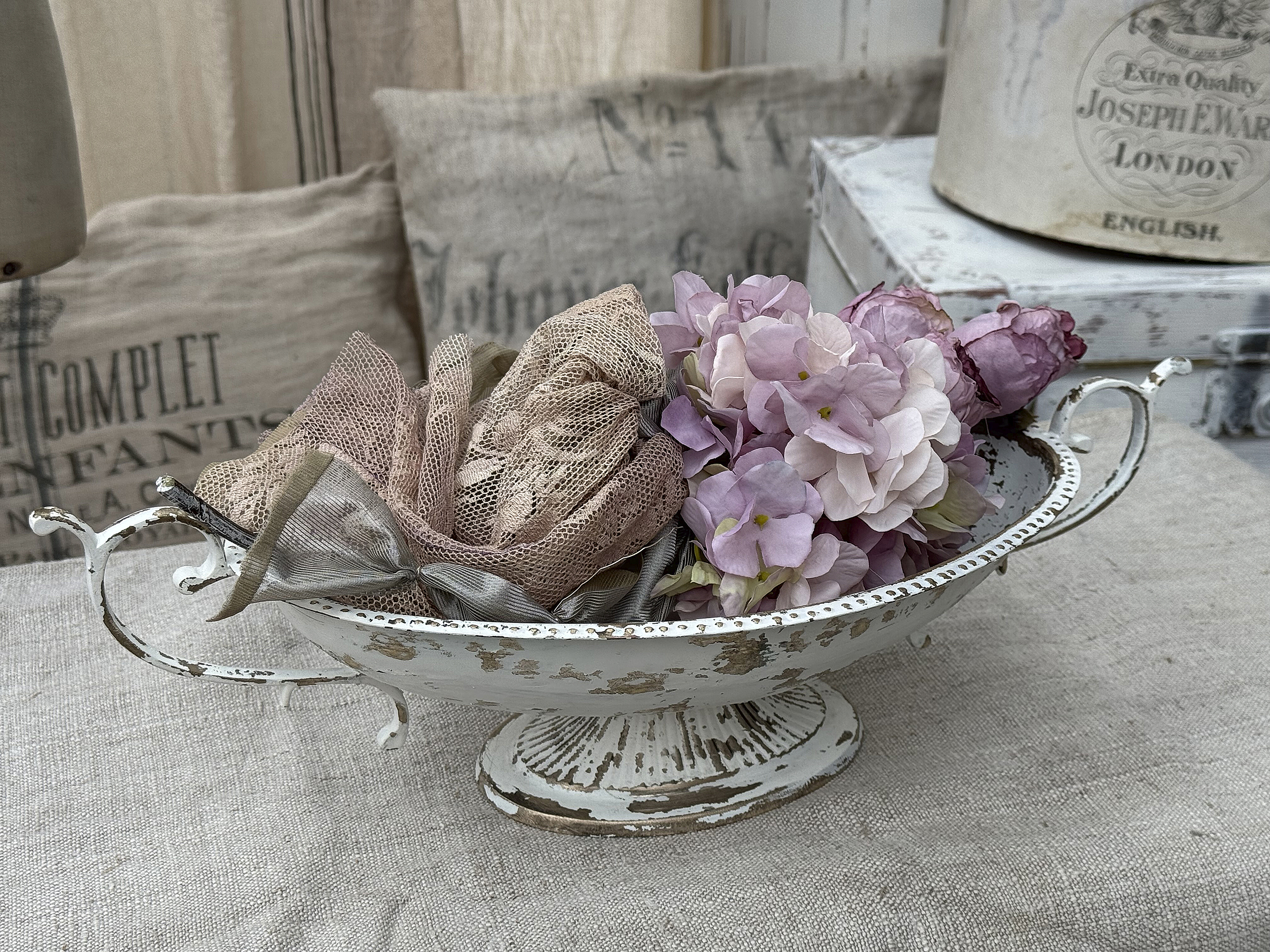 Schöner Blumenschmuck in einem antiken Behälter mit Stoffbändern in sanften Farben