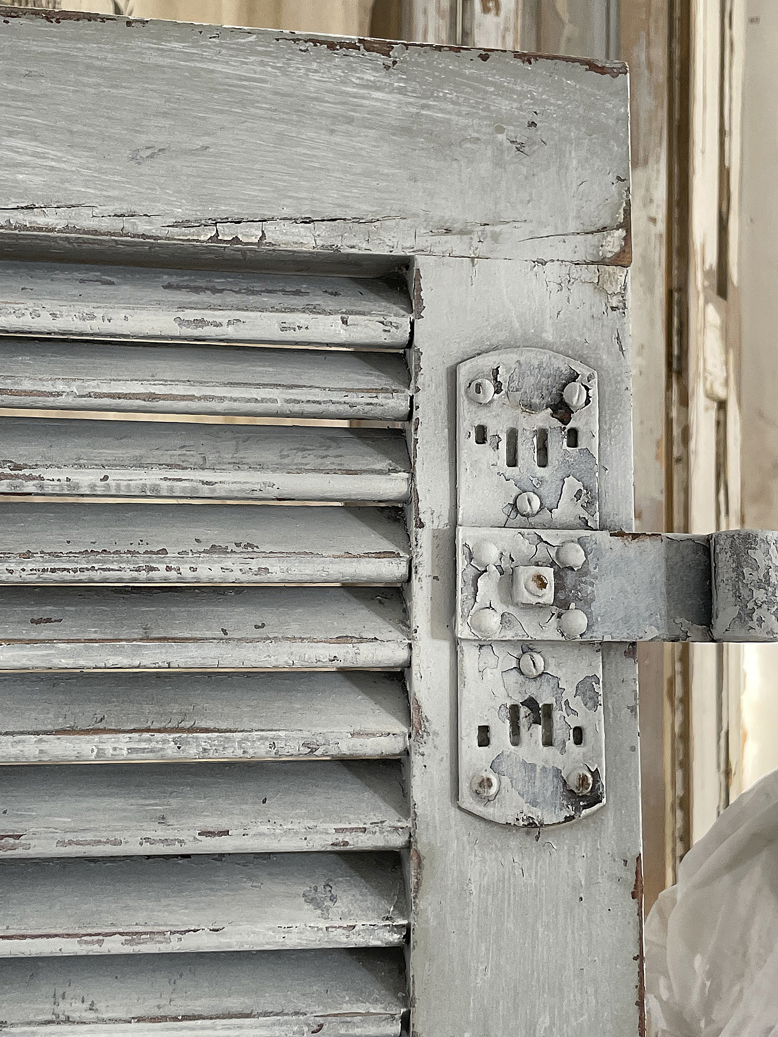Detailaufnahme eines alten, grauen Fensterladens mit Rost und Abnutzungsspuren Alter, grauer Fensterladen mit sichtbaren Kratzern und beschädigtem Lack in Nahaufnahme