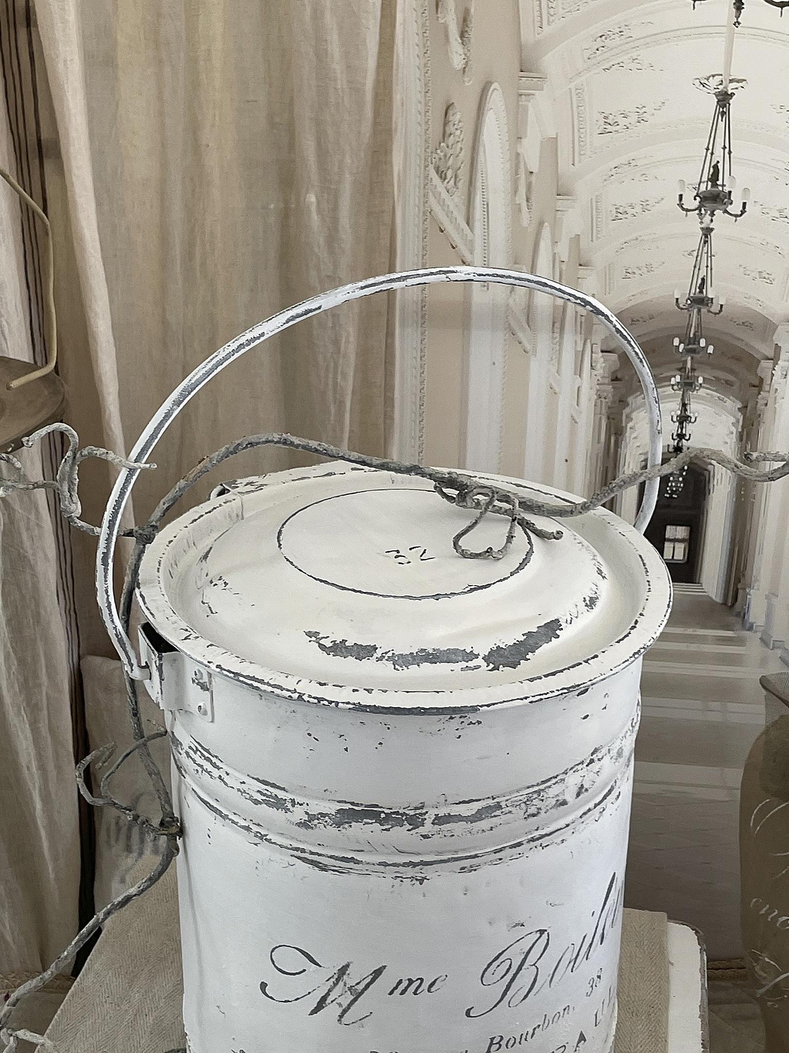 Dekorativer vintage Eimer mit weißer Farbe und nostalgischem Design Weißer, vintage Eimer mit nostalgischer Beschriftung in einer eleganten Umgebung