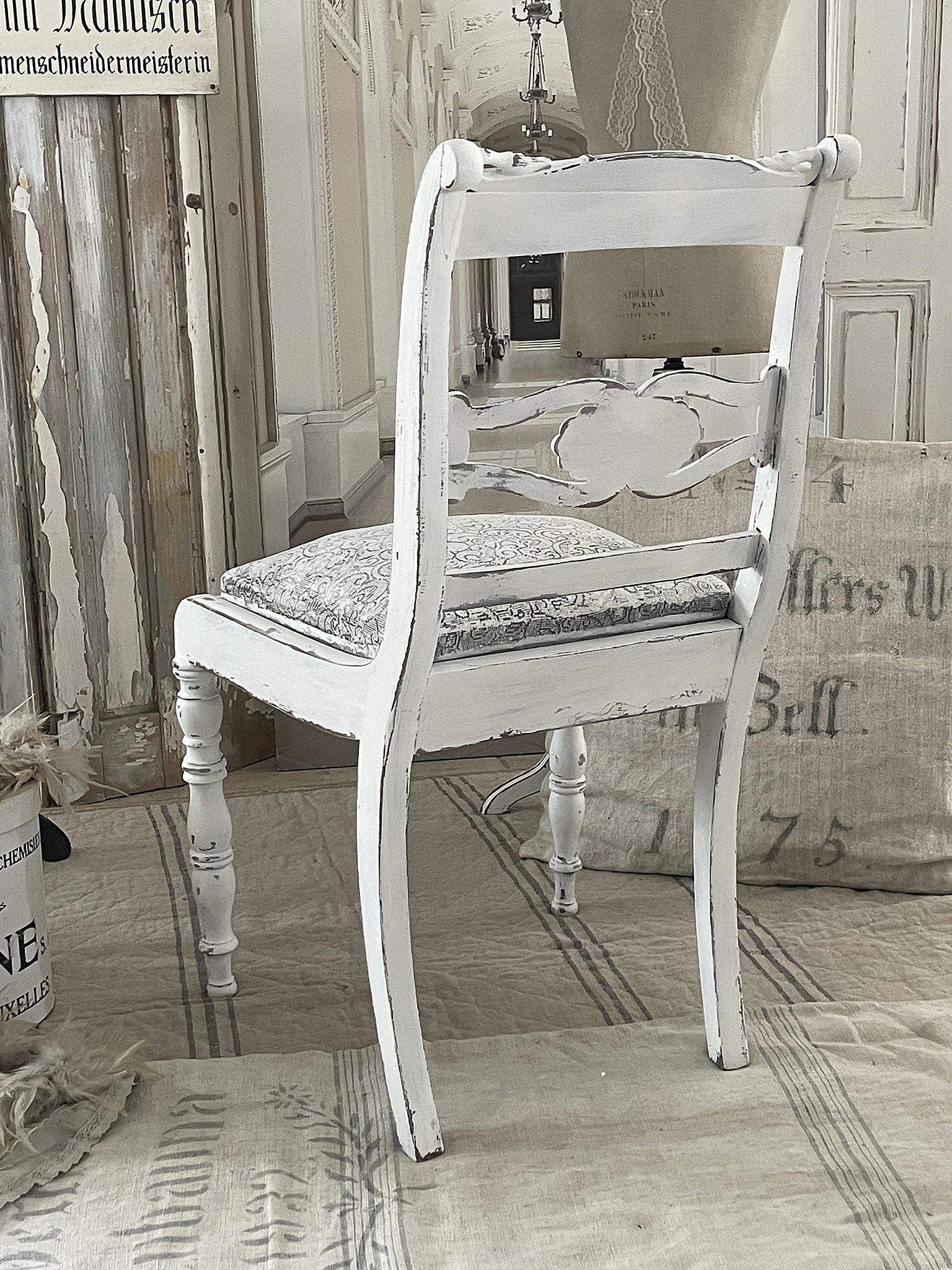 Vintage Stuhl mit verziertem Rücken und gepolsterter Sitzfläche Eleganter, vintage Stuhl mit weißer Farbe und floralem Muster auf der Sitzfläche